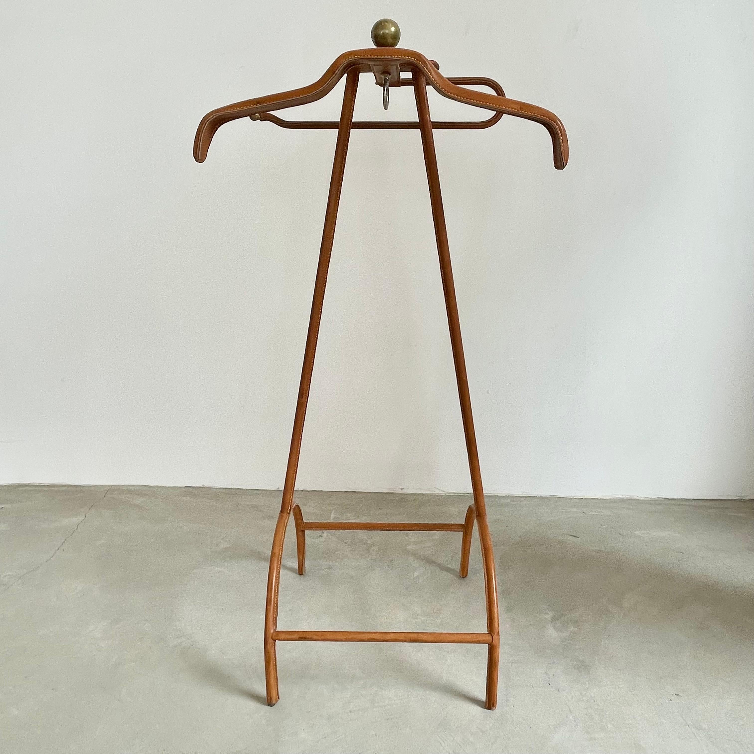 Stunning coat stand / valet by French modernist designer, Jacques Adnet. Valet has an iron frame with brass accents including brass ball feet, brass ball at the end of the pant rod and a large brass ball adorning the top of the valet. Entire frame