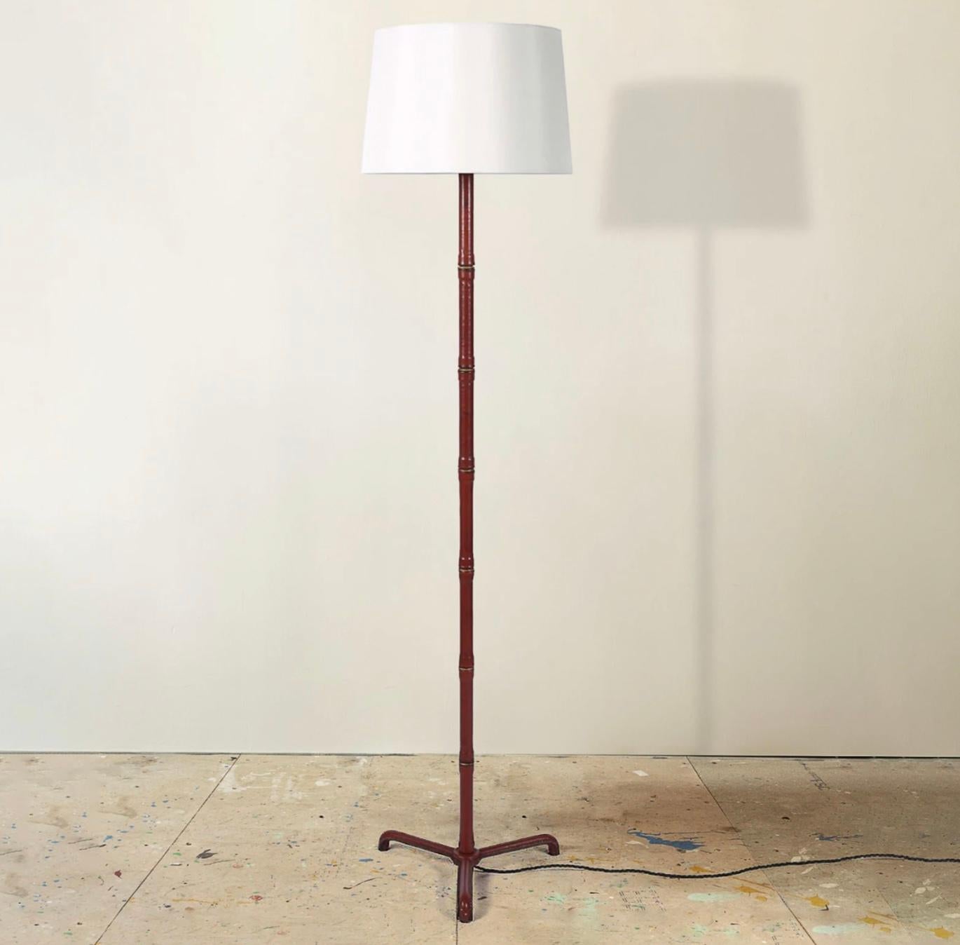 A very good floor lamp, the hand stitched scarlet goatskin leather alternating with brass rings to simulate bamboo.

Designed by Jacques Adnet, c. French 1950s.

Measure: Height to top of bulb holder 160cm.

Supplied with a silk dupion shade