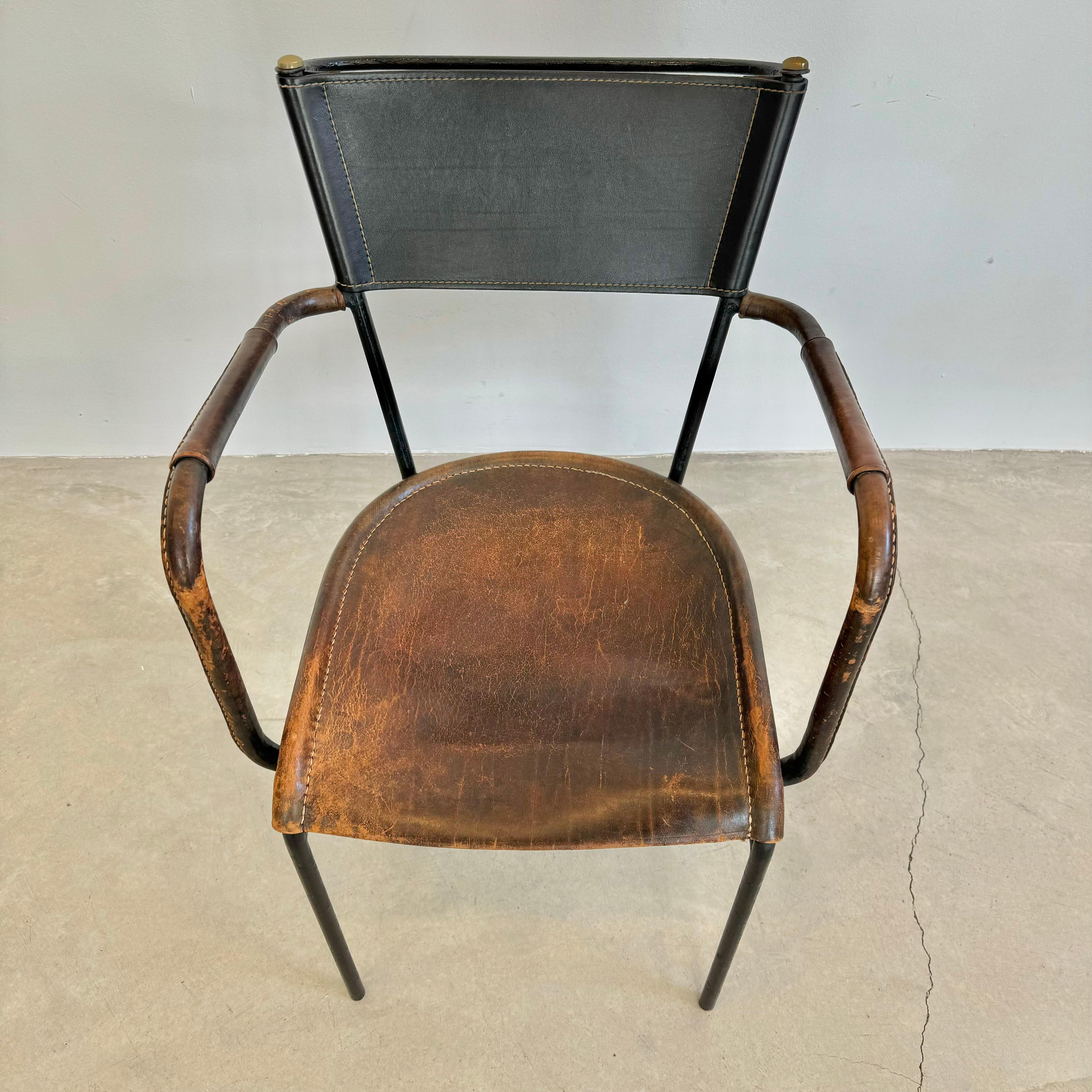 Stunning chair by French designer Jacques Adnet. Black metal tube frame with leather seat, leather seat back and leather wrapped armrests. Chair features a beautiful wing loop armrest design with an additional iron handle on the backrest secured to