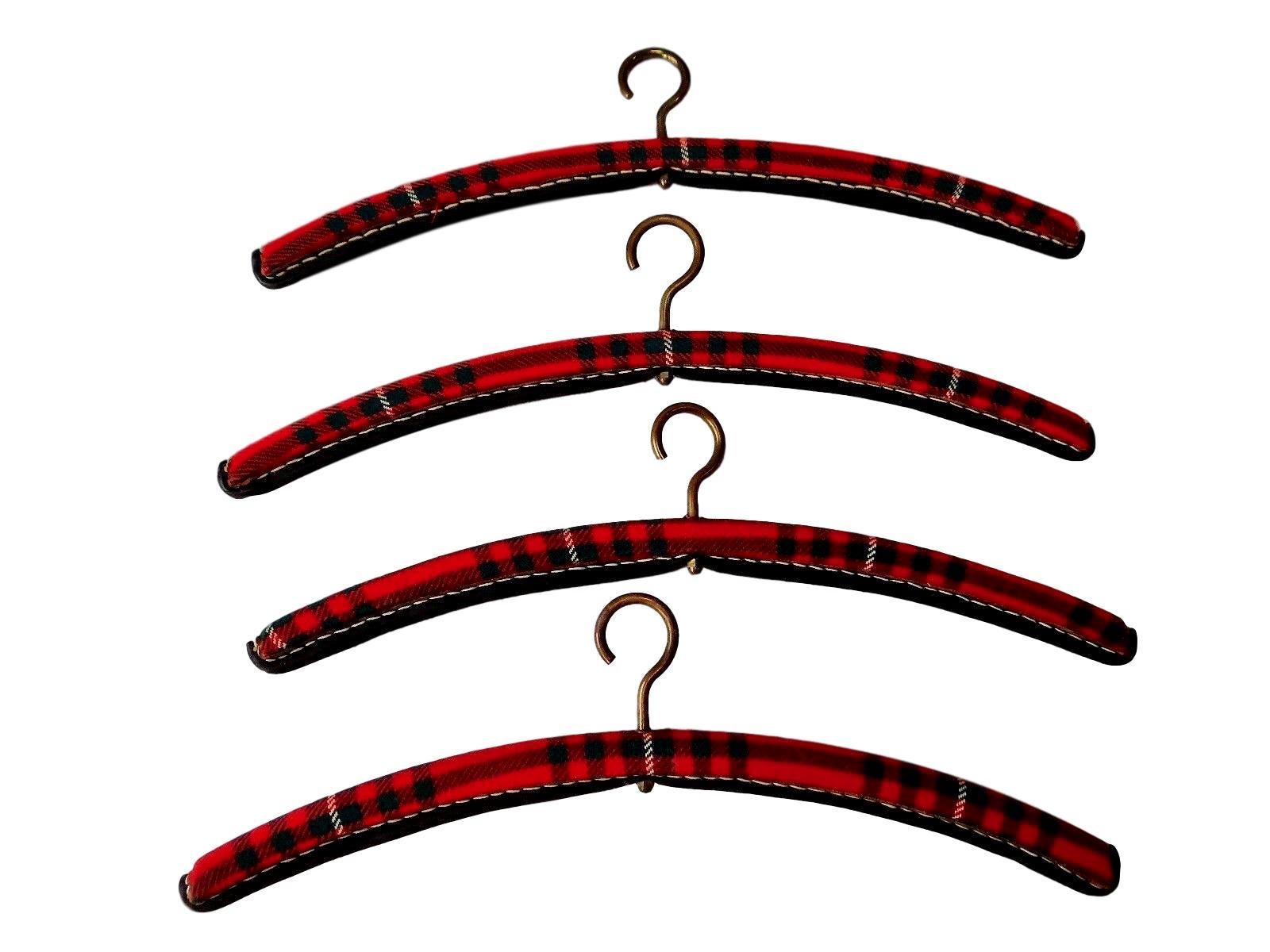 Rare coat hangers by French designer Jacques Adnet. Brass hardware with black leather, red tweed, and signature contrast stitching. Excellent vintage condition. Sold individually, 4 still available. 

