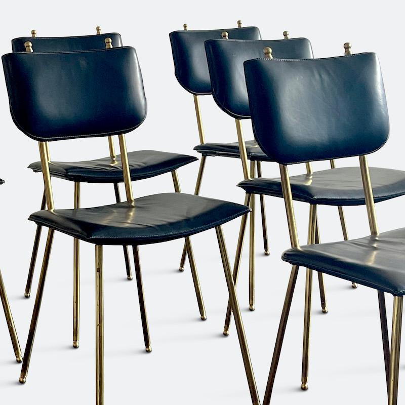 An exquisite set of six Jacques Adnet dining chairs dating from the 1950s. Upholstered in black leather, accented with white stitching, held with banded leather to the kink of the leg, sheathed in unpolished patinated brass. Signature use of ball