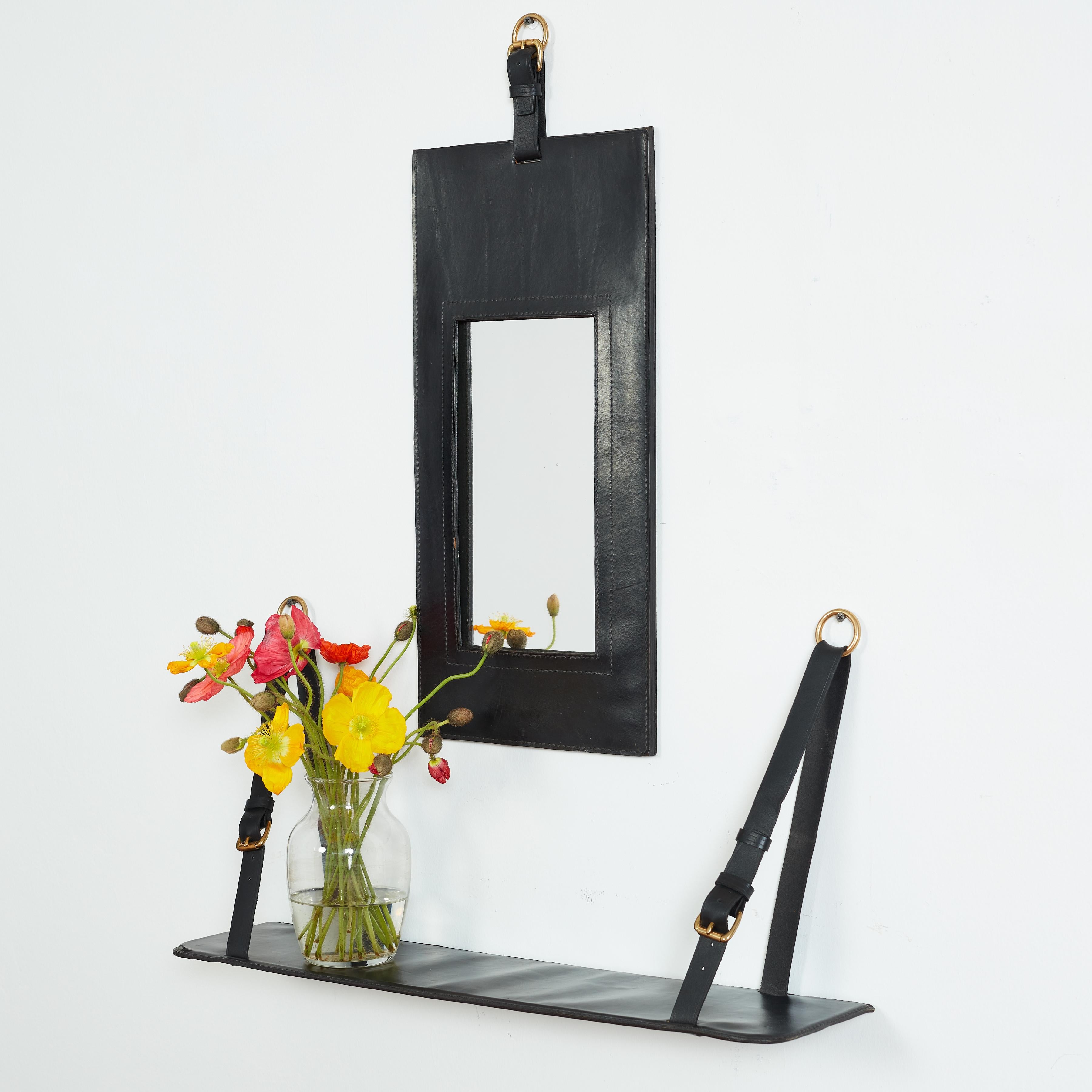 Jacques Adnet black leather framed mirror with black leather floating shelf.

Brass hardware. 

Mirror - 11