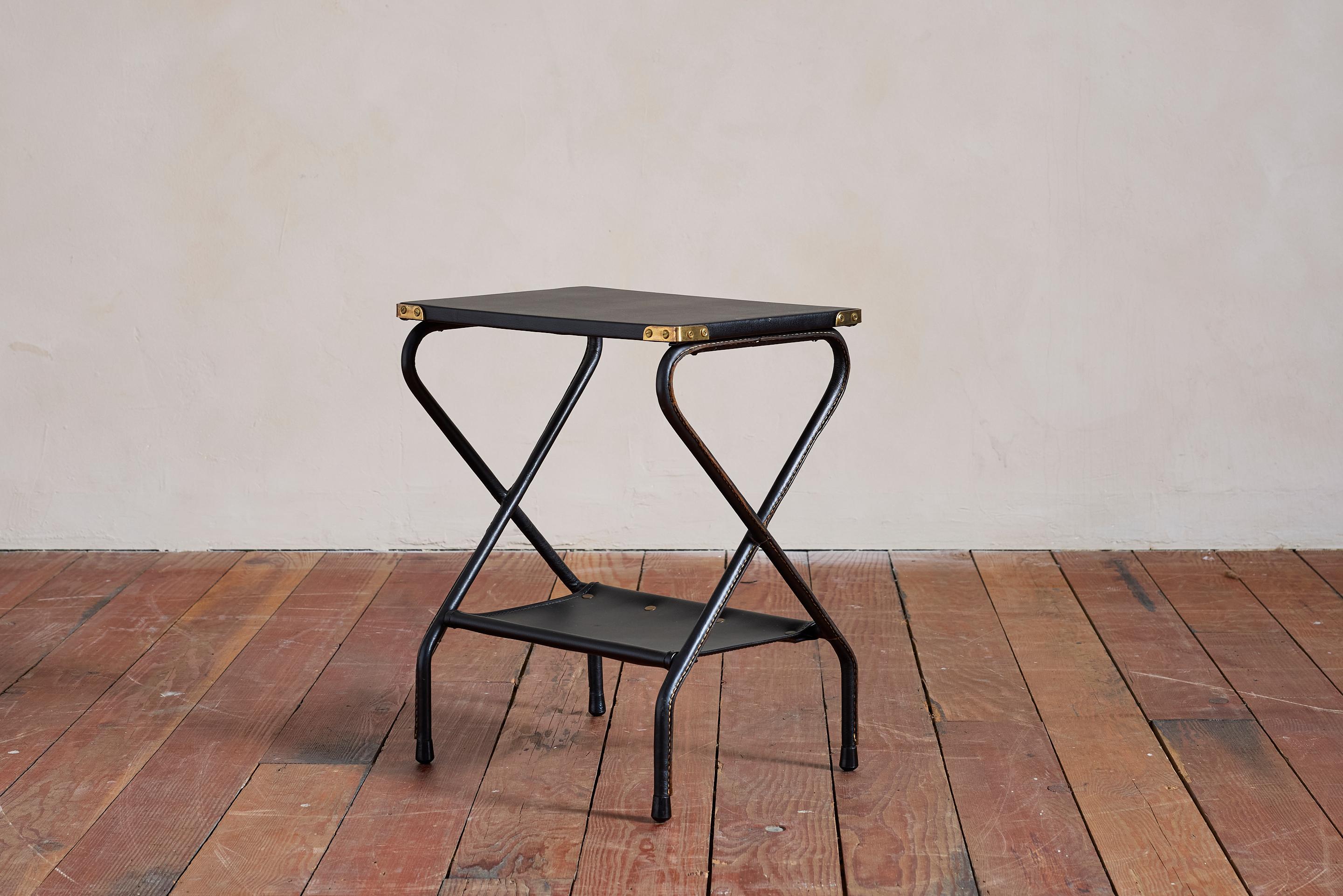 Great petite side table by Jacques Adnet with floating shelf 
Signature contrast stitching and brass corners. 



