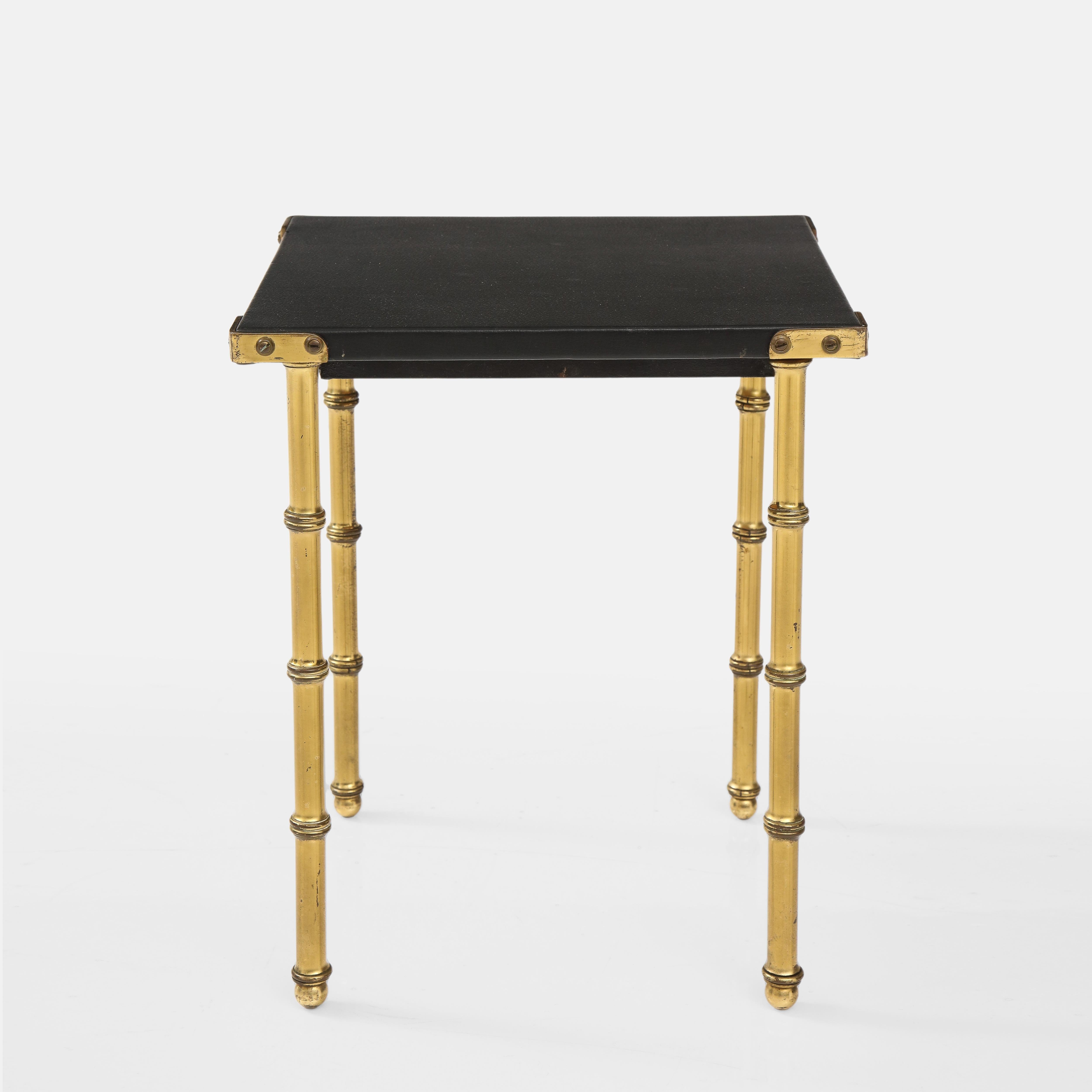 Jaques Adnet small side table with top wrapped in original black skaï and faux bamboo brass legs. It's a fine example of iconic French post-war Adnet design in which pieces of furniture, lighting and accessories were meticulously clad in