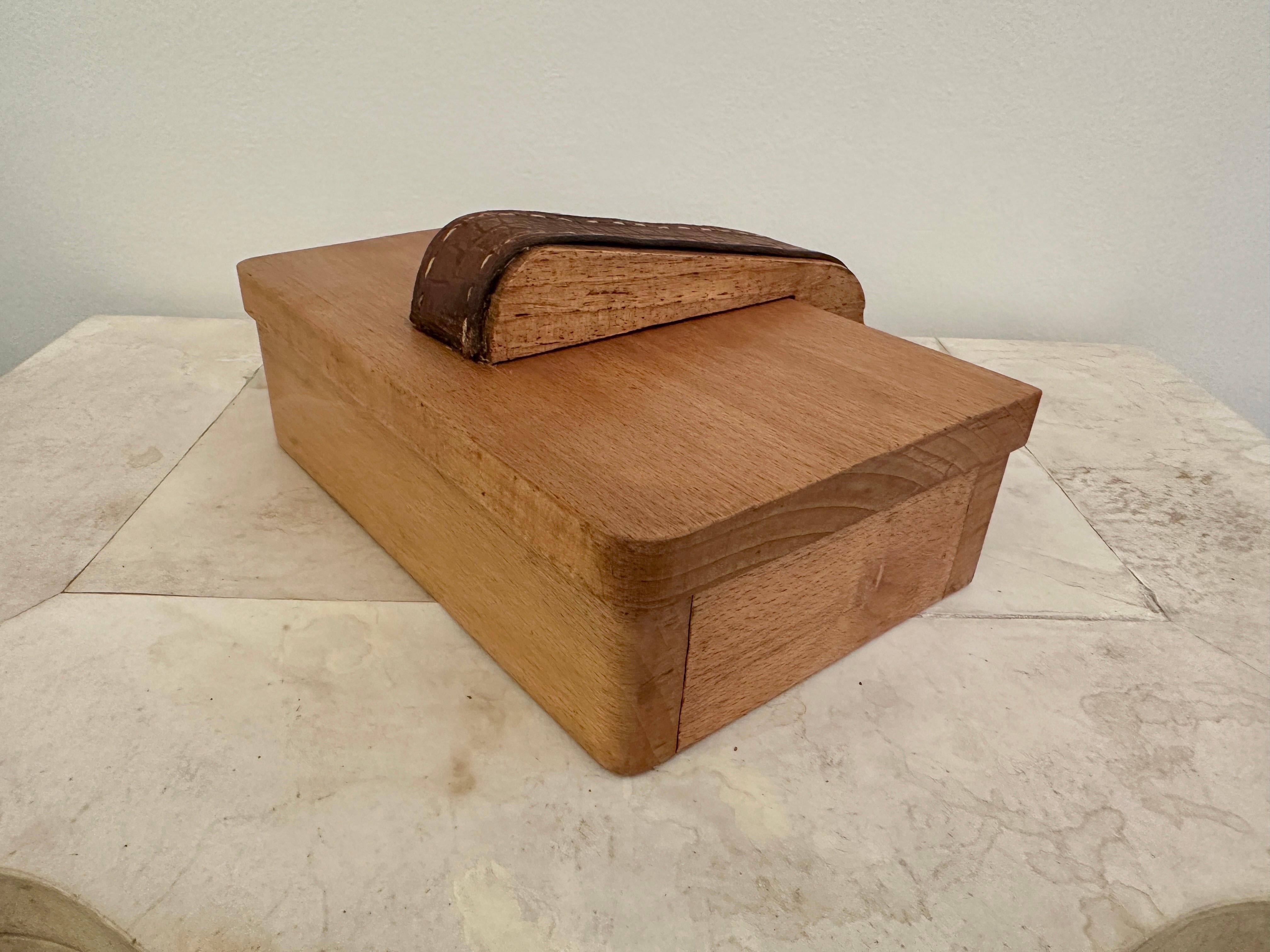 Hermosa simplicidad del diseño de Jacques Adnet, esta caja con bisagras, con ribetes y pespuntes de cuero marrón clásico, está marcada en la parte inferior.  