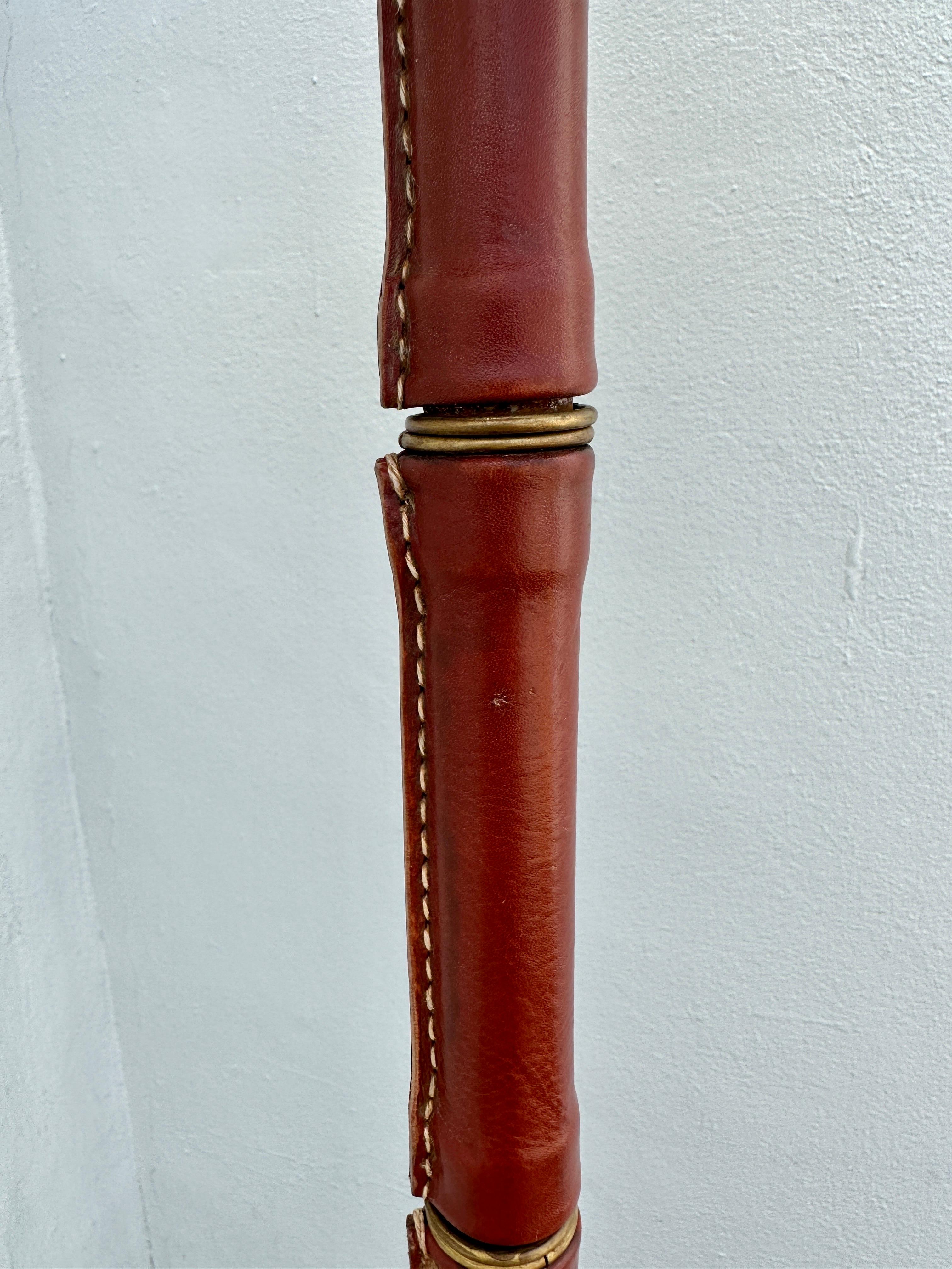 This all vintage maroon leather floor lamp by Jacques Adnet - newly rewired with brown twisted silk cable. Shade shown is seagrass and is included upon request.  THIS ITEM IS LOCATED AND WILL SHIP FROM OUR EAST HAMPTON, NY SHOWROOM.