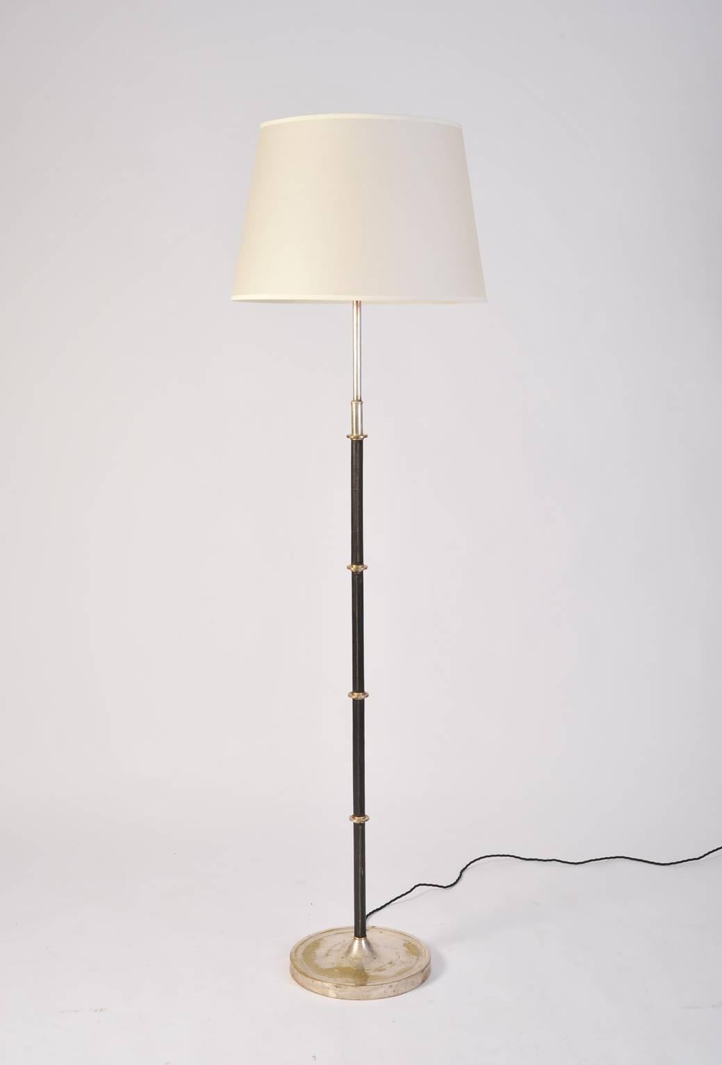 A stitched black leather and silvered brass floor lamp, in the manner of Jacques Adnet (1901-1984)
France, circa 1950.
