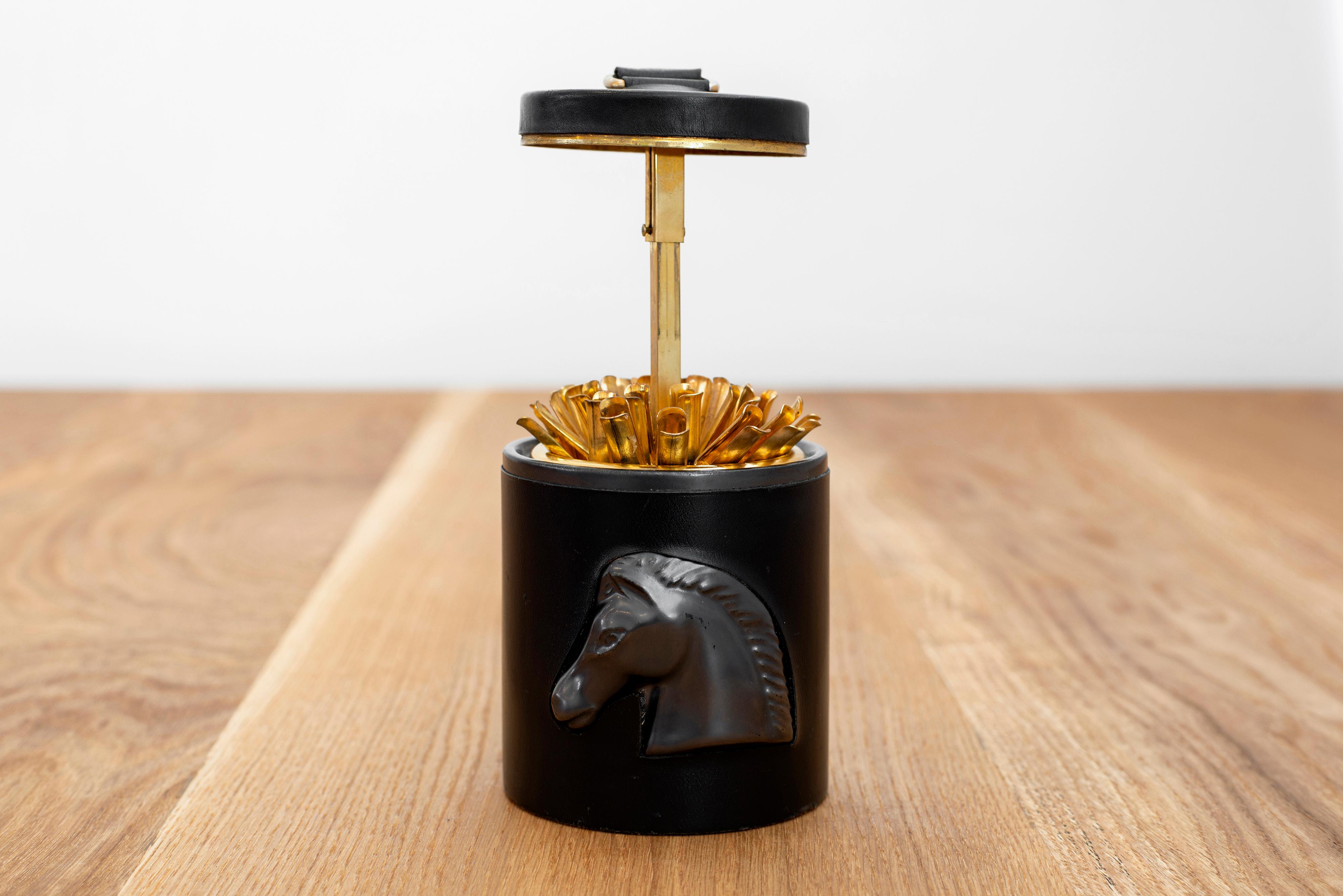 Great cigarette holder in the style of Jacques Adnet with horse head relief.
The leather top pops up to reveal brass individual cases to hold cigarettes.
enameled ceramic inside and leather with contrast saddle stitching on outside.
Great gift