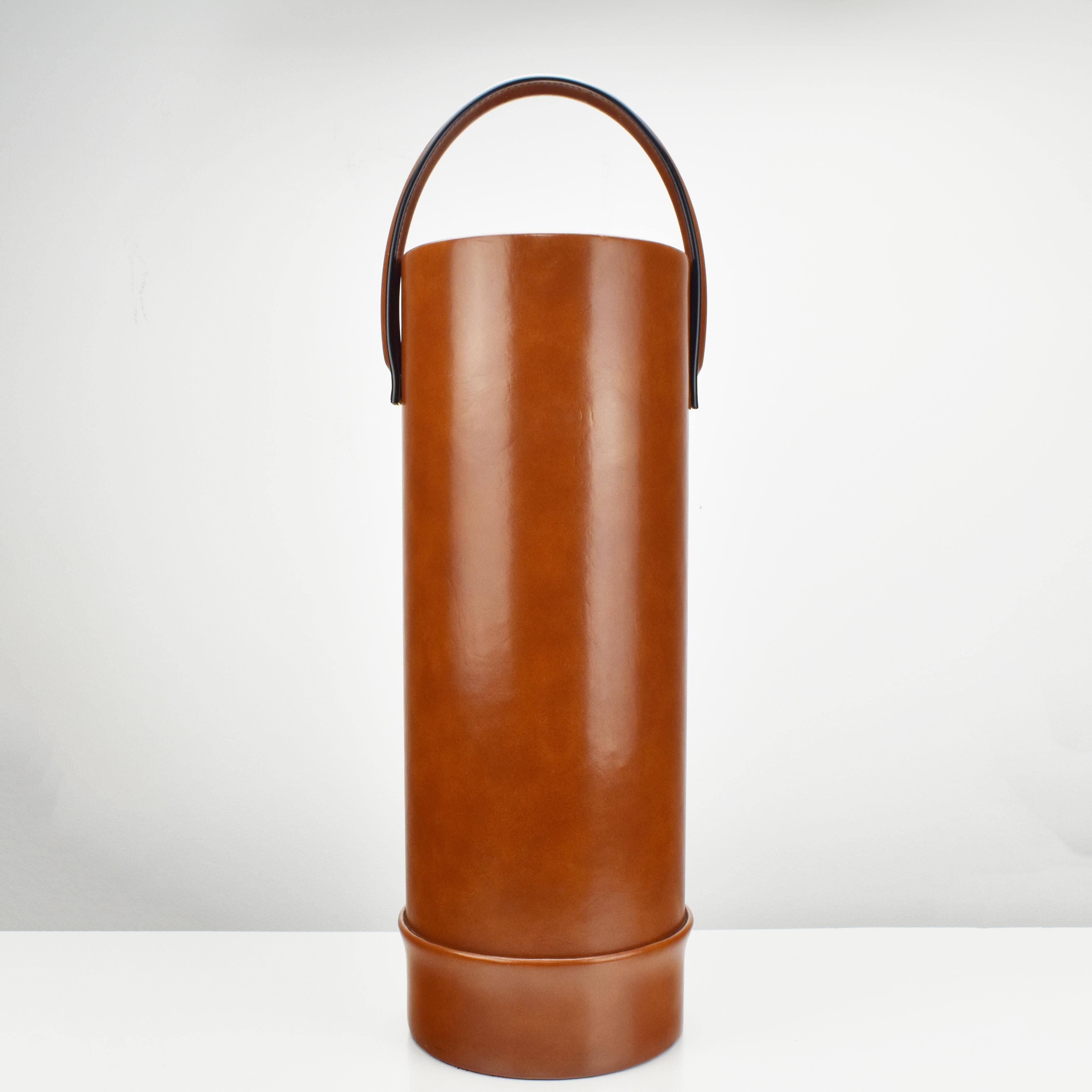 A vintage Jacques Adnet style umbrella stand or waste basket with a movable handle, made of cognac colored faux leather with cream colored contrast stitching by unknown manufacturer, dating to the 1960s.