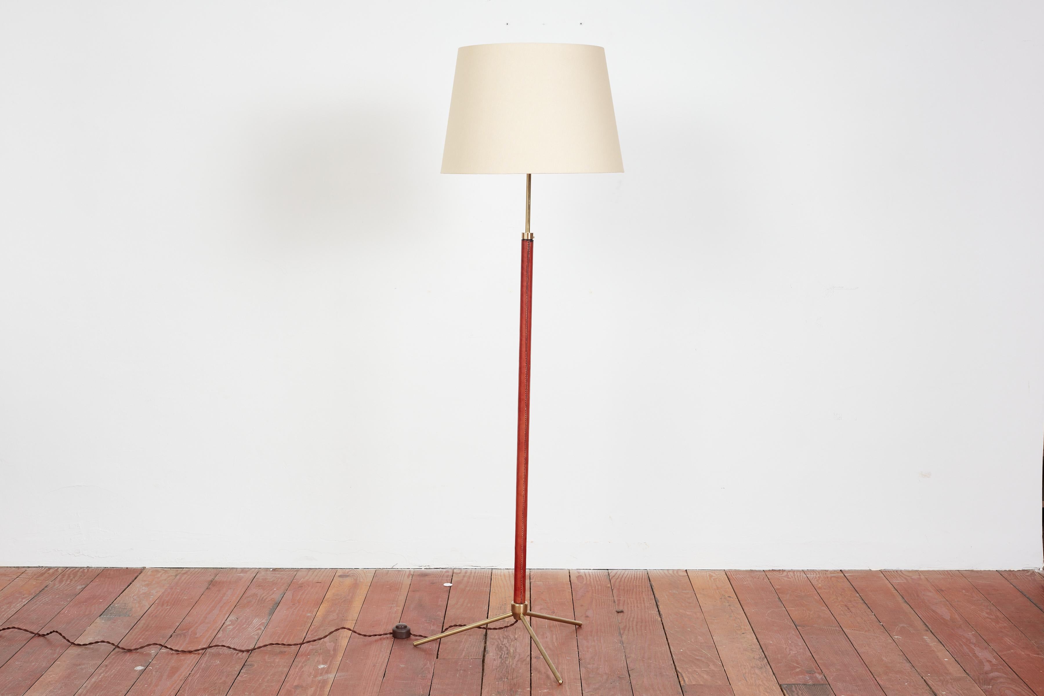 Handsome French floor lamp by Jacques Adnet.

Signature hand-stitched Caramel Brown leather, contrast stitching, brass tripod base and new silk shade. 

Newly rewired. 