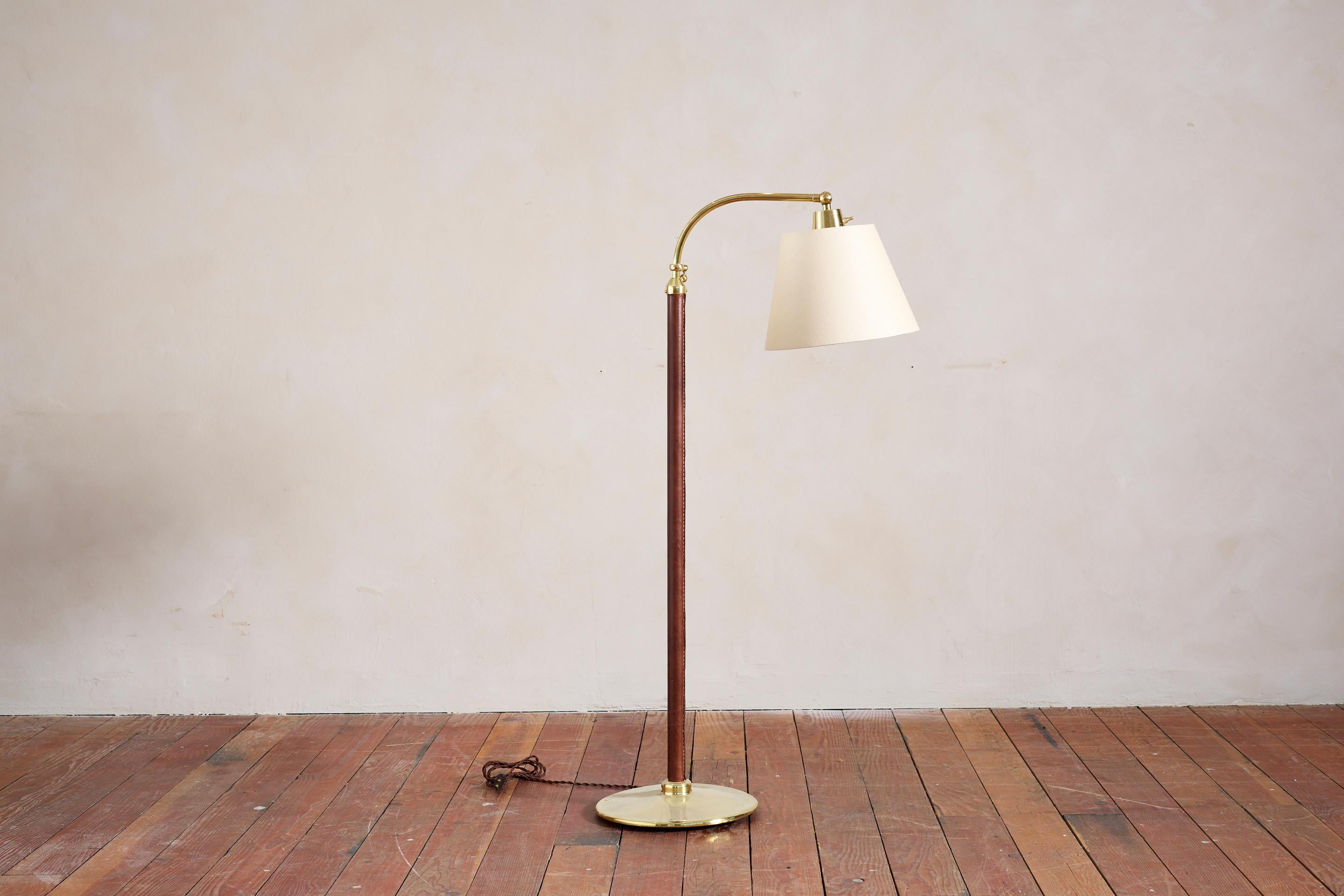 Lampadaire de style Jacques Adnet en cuir couleur caramel foncé avec base ronde et quincaillerie en laiton poli.

Mécanisme de réglage de la hauteur
Nouvel abat-jour en lin

Hauteur de la lampe 51