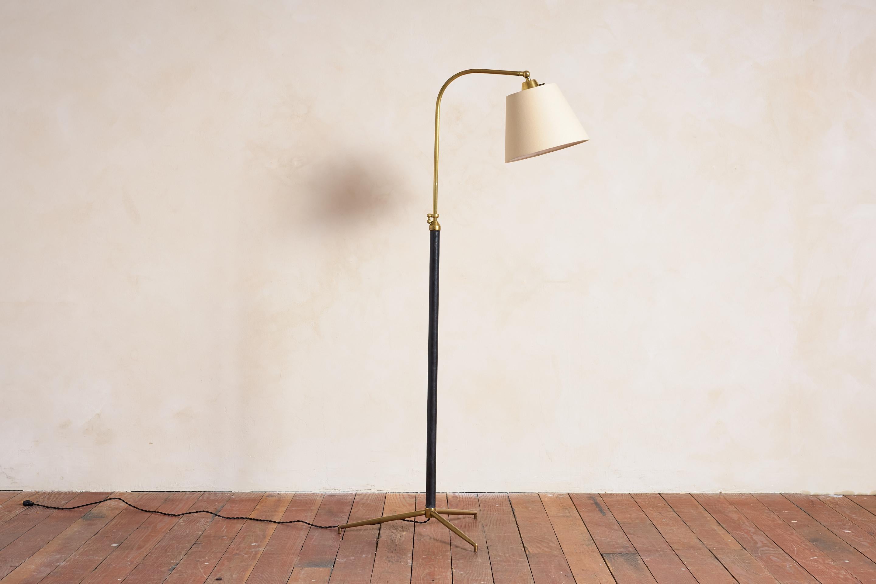 Handsome French floor lamp by Jacques Adnet with hand-stitched black leather, brass tripod base and new silk shade. 

Newly rewired.

Height extends from 54” - 69.5”