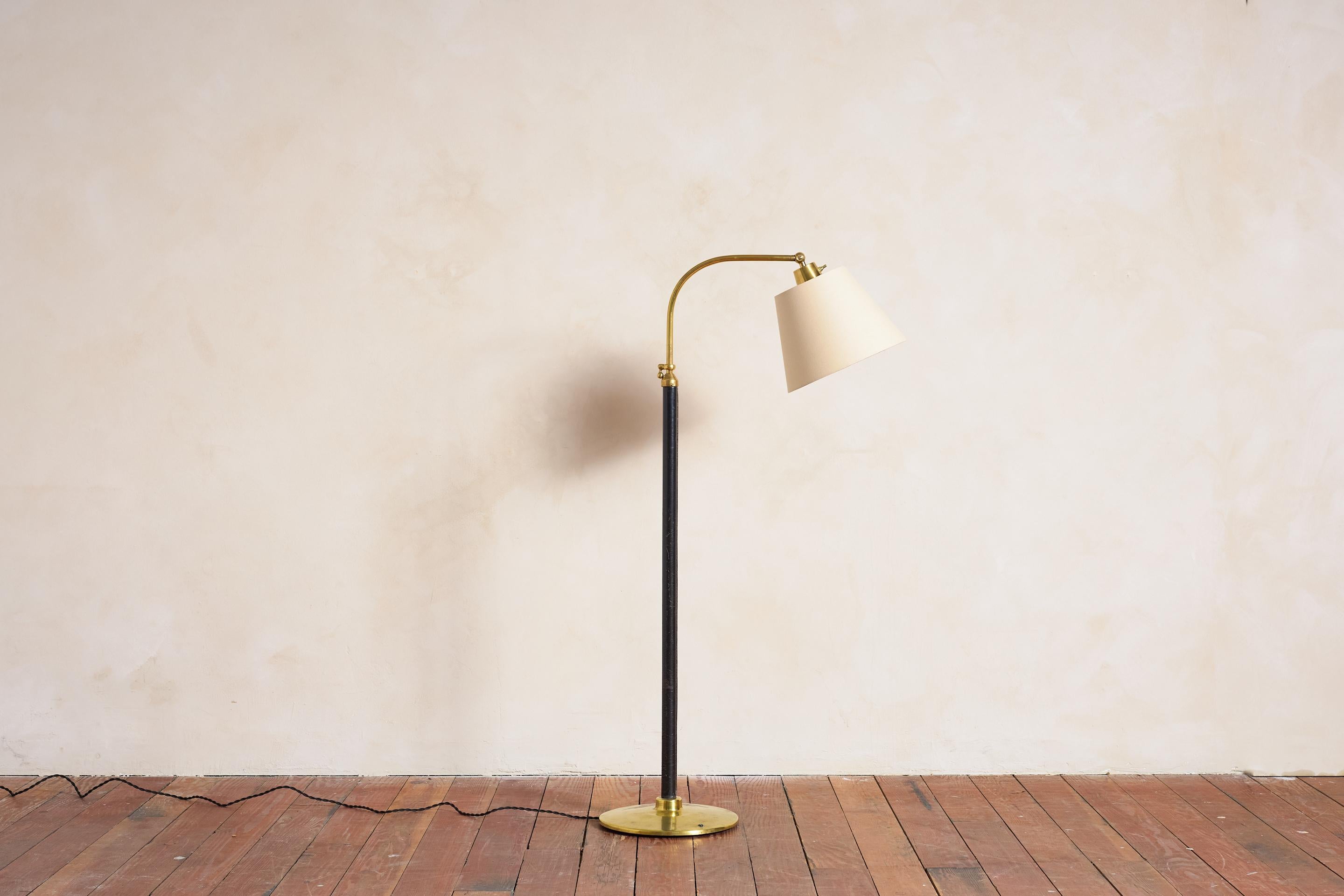 Lámpara de pie estilo Jacques Adnet en piel de color negro con base redonda y herrajes de latón pulido.

Mecanismo de altura regulable

Nueva pantalla de lino

Altura de la lámpara 53,5