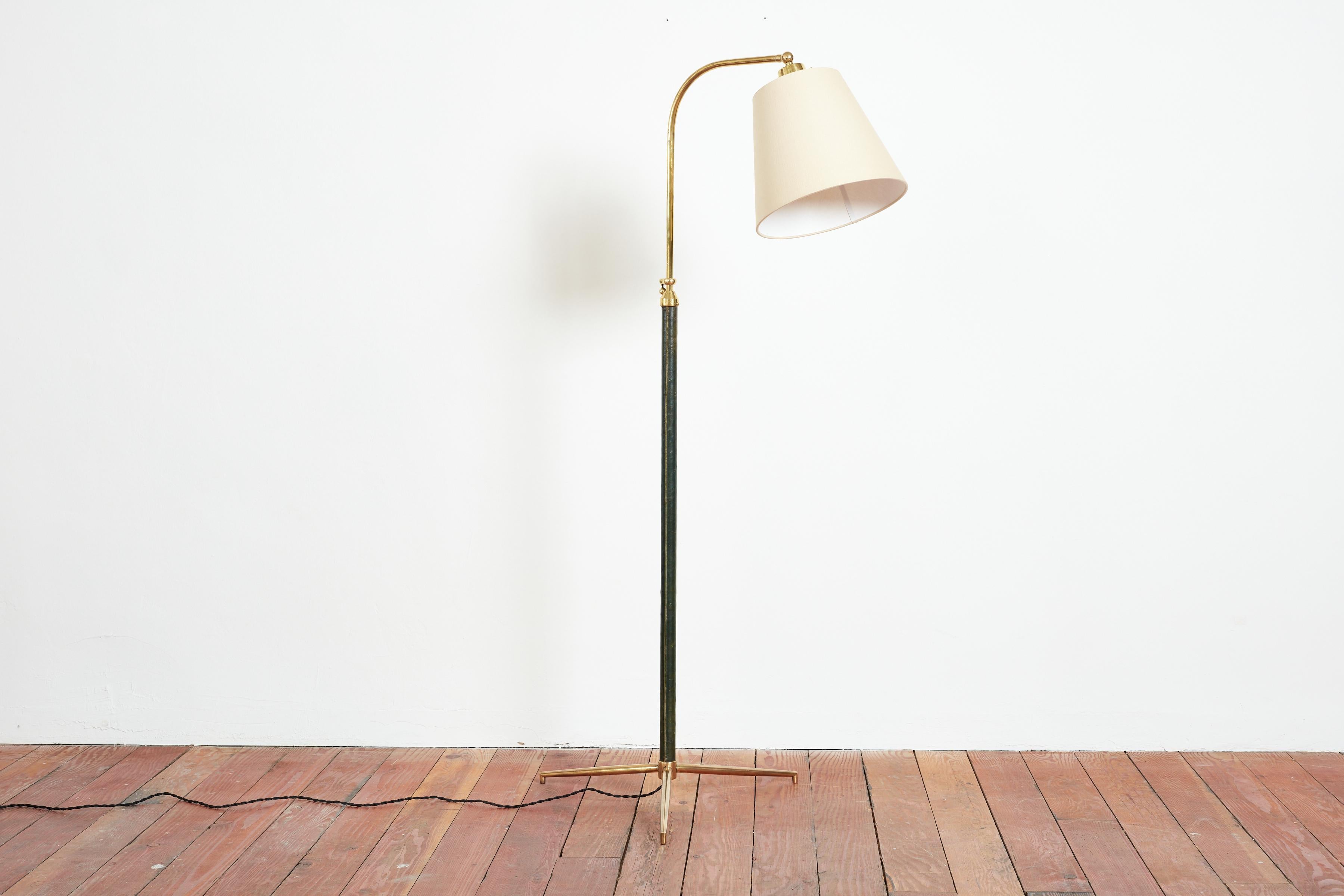 Handsome French floor lamp by Jacques Adnet with hand-stitched dark green leather, contrast stitching, brass tripod base and new linen shade.

Wonderful color of green leather and articulating shade

Newly rewired.

Height extends from 48” - 64.5”.