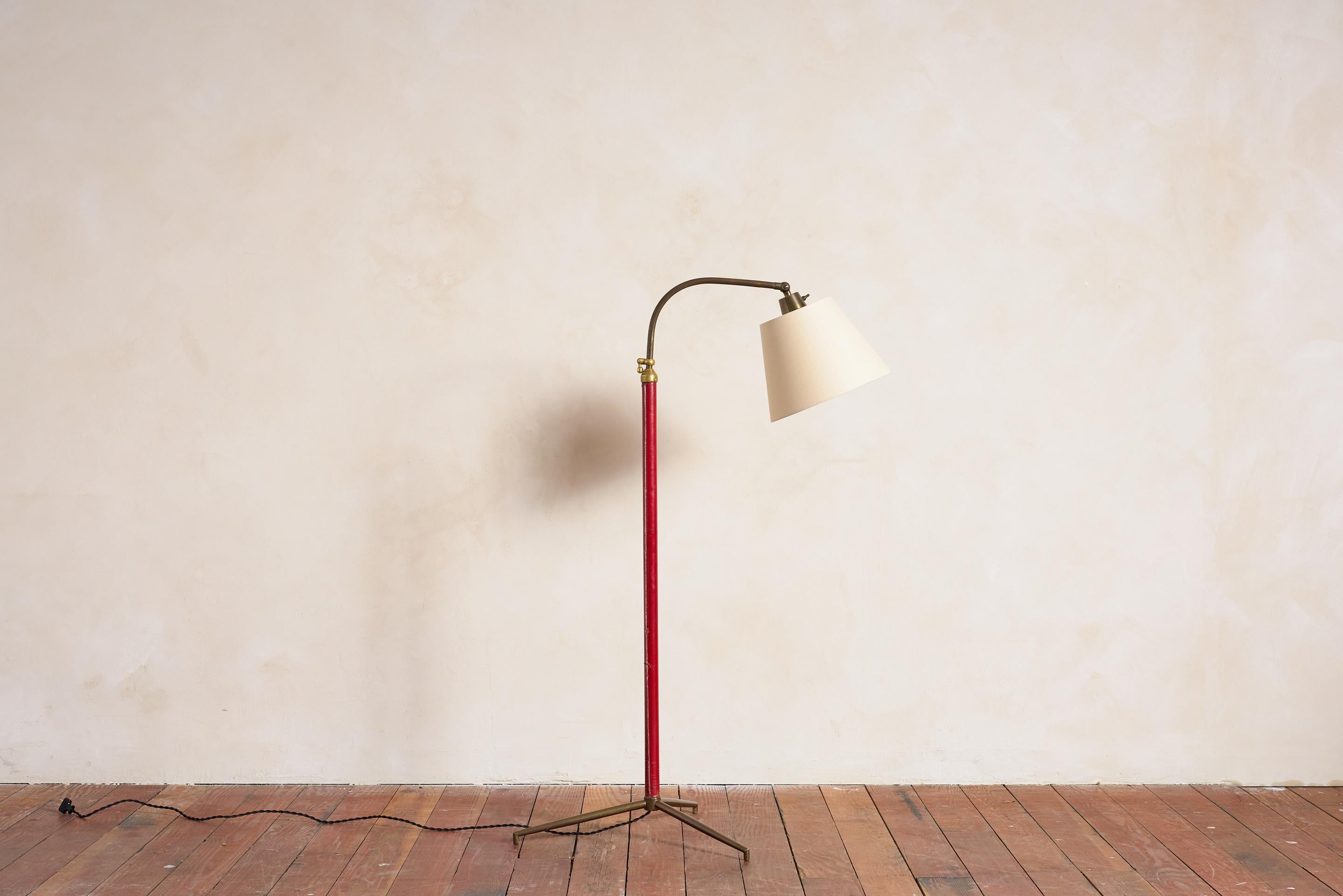 Beau lampadaire français de Jacques Adnet avec cuir rouge cousu à la main, base tripode en laiton et abat-jour en soie neuve. 

Nouvellement recâblé. 

La hauteur s'étend de 48,5