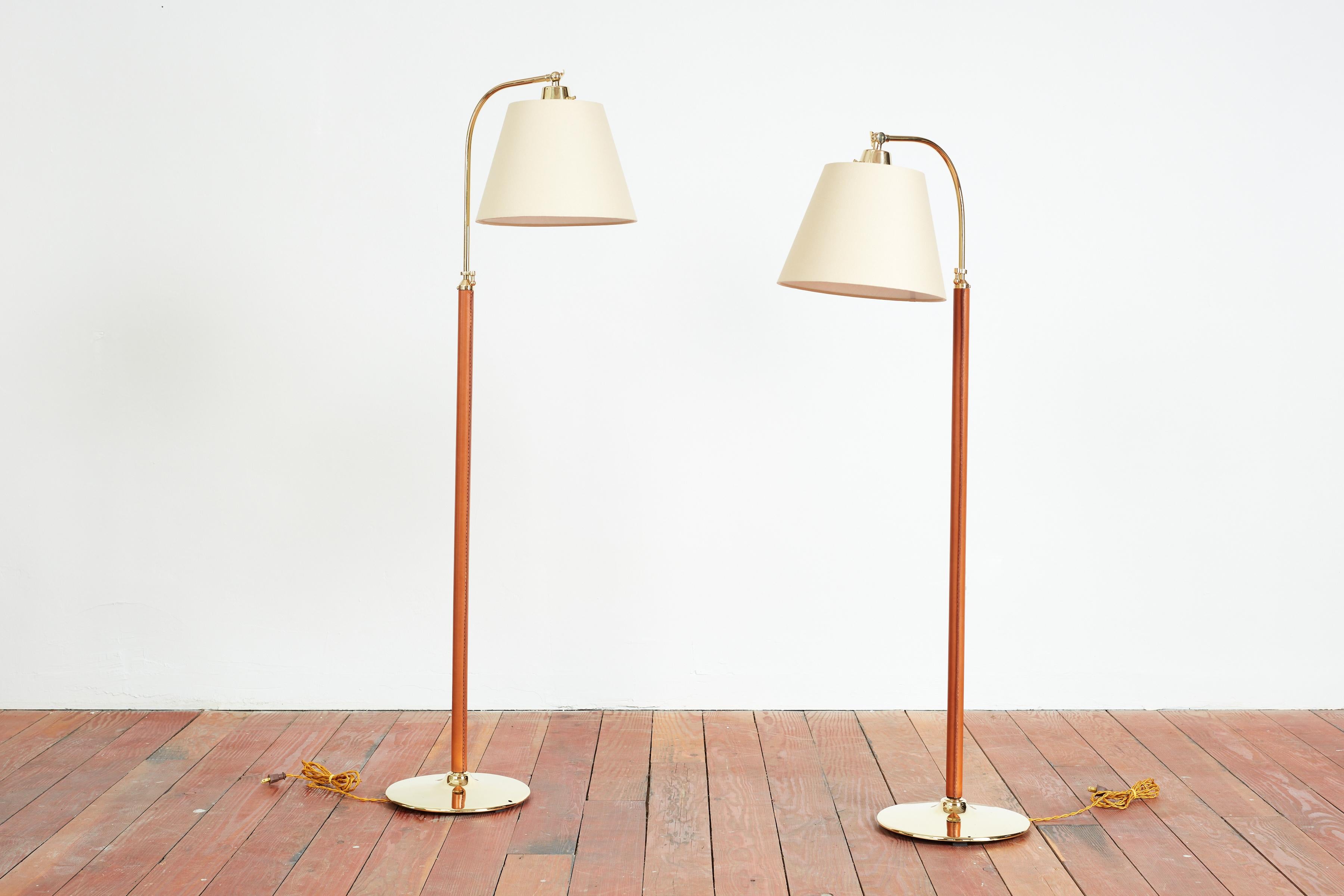 Matching pair (sold separately) of floor lamps attributed to Jacques Adnet
Caramel colored leather with polished brass round base and hardware.
Adjustable height mechanism
New linen shade

Lamp Height 50 1/2