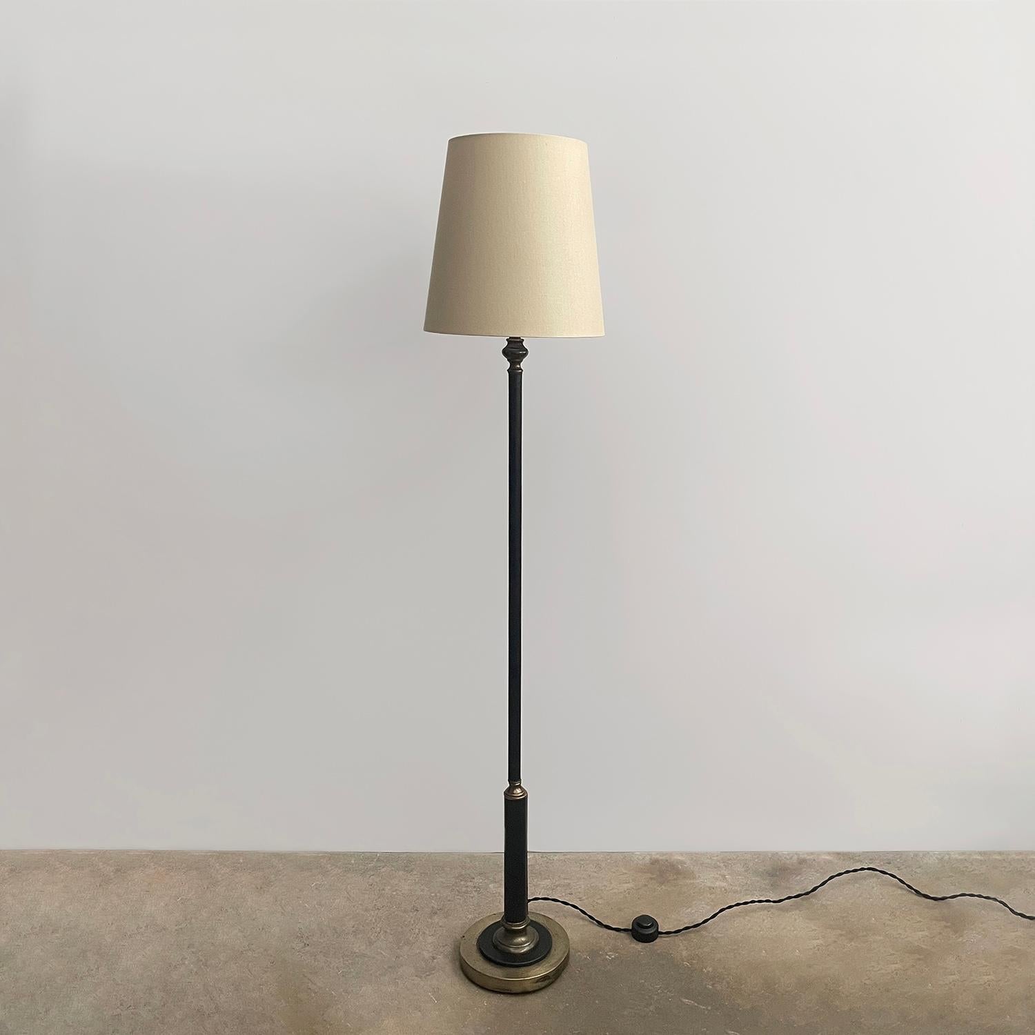 Lampadaire en cuir et laiton dans le style de Jacques Adnet
Lampadaire élégant et raffiné 
La tige enveloppée de cuir noir est rehaussée de surpiqûres contrastées.
Base en laiton vieilli avec détails en cuir
Patine d'âge et d'utilisation 
Nouveau