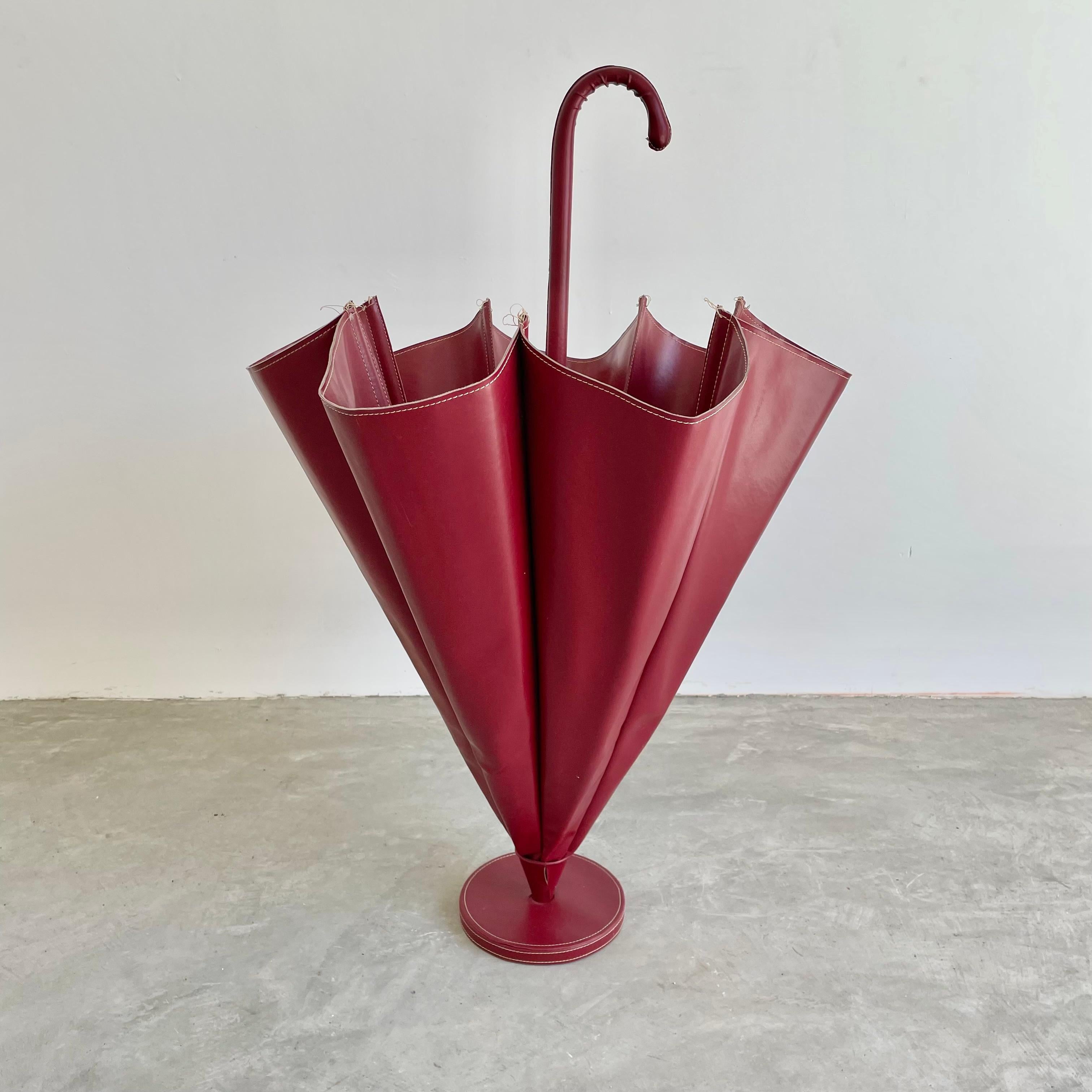 Stunning umbrella stand in the style of Jacques Adnet. Red Skai material with Adnet style contrast stitching. Styled in the shape of an upside down, open umbrella. Completely wrapped in Skai. 6 removable metal cups sit at the bottom of each fold to
