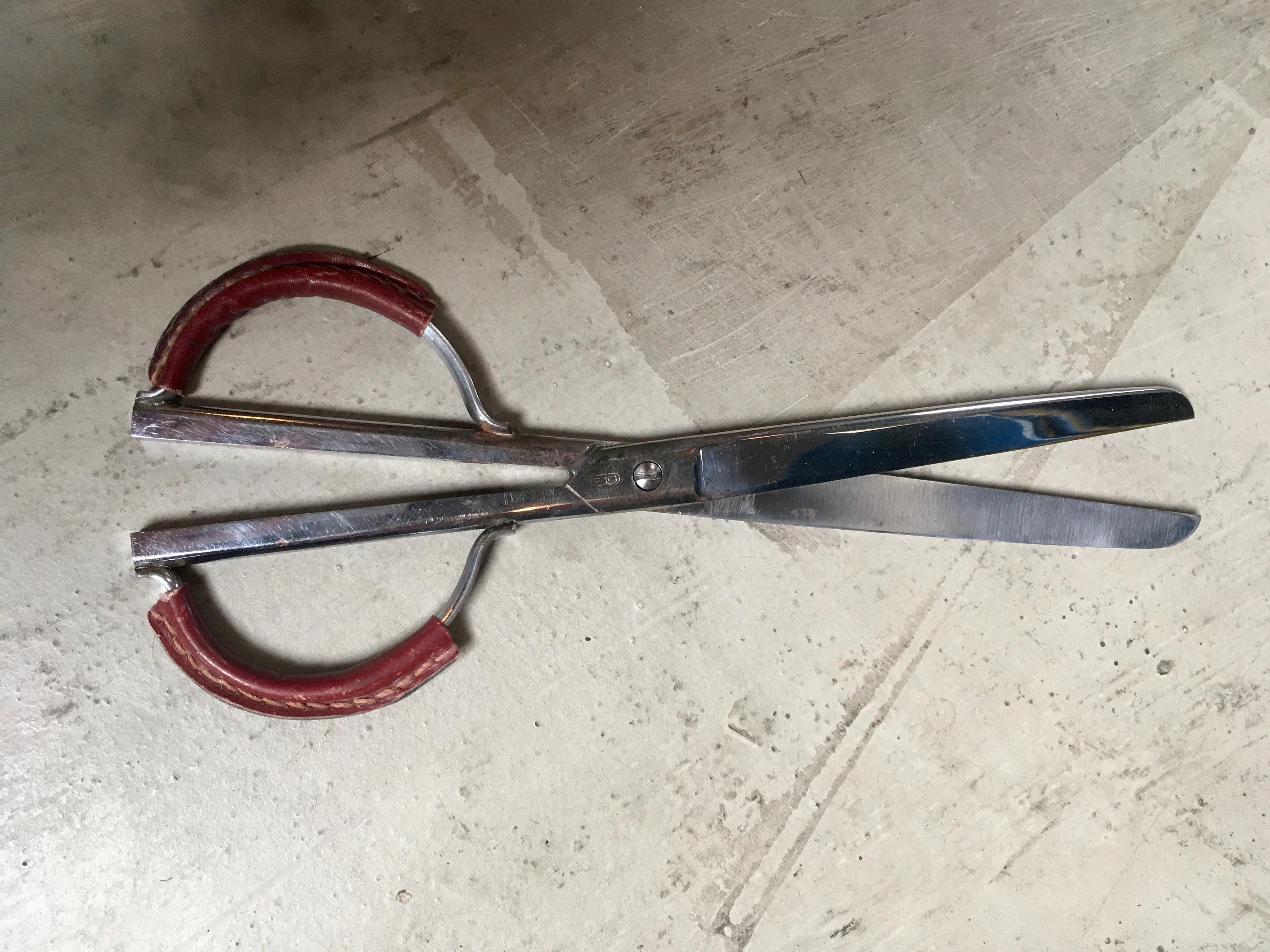 Handsome nickel scissors with leather wrapped handles in the style of Jacques Adnet. Burgundy leather with signature Adnet stitching. Good vintage condition.