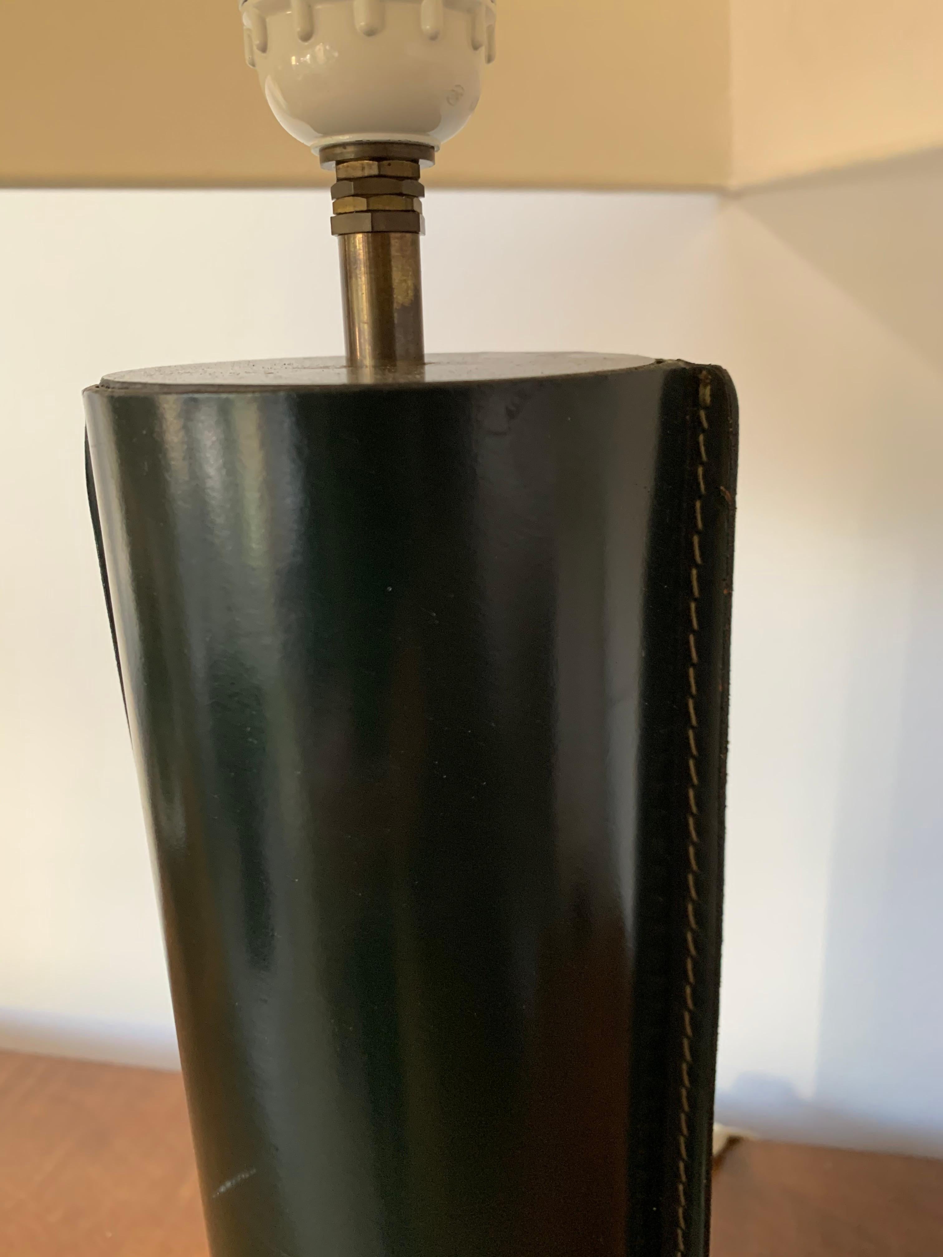 This Jacques Adnet style table lamp has a black leather-wrapped base and brass details. Great stylish object! Clean lines and simple forms - these are the hallmarks of the style of this outstanding designer and this lamp is very good example of this