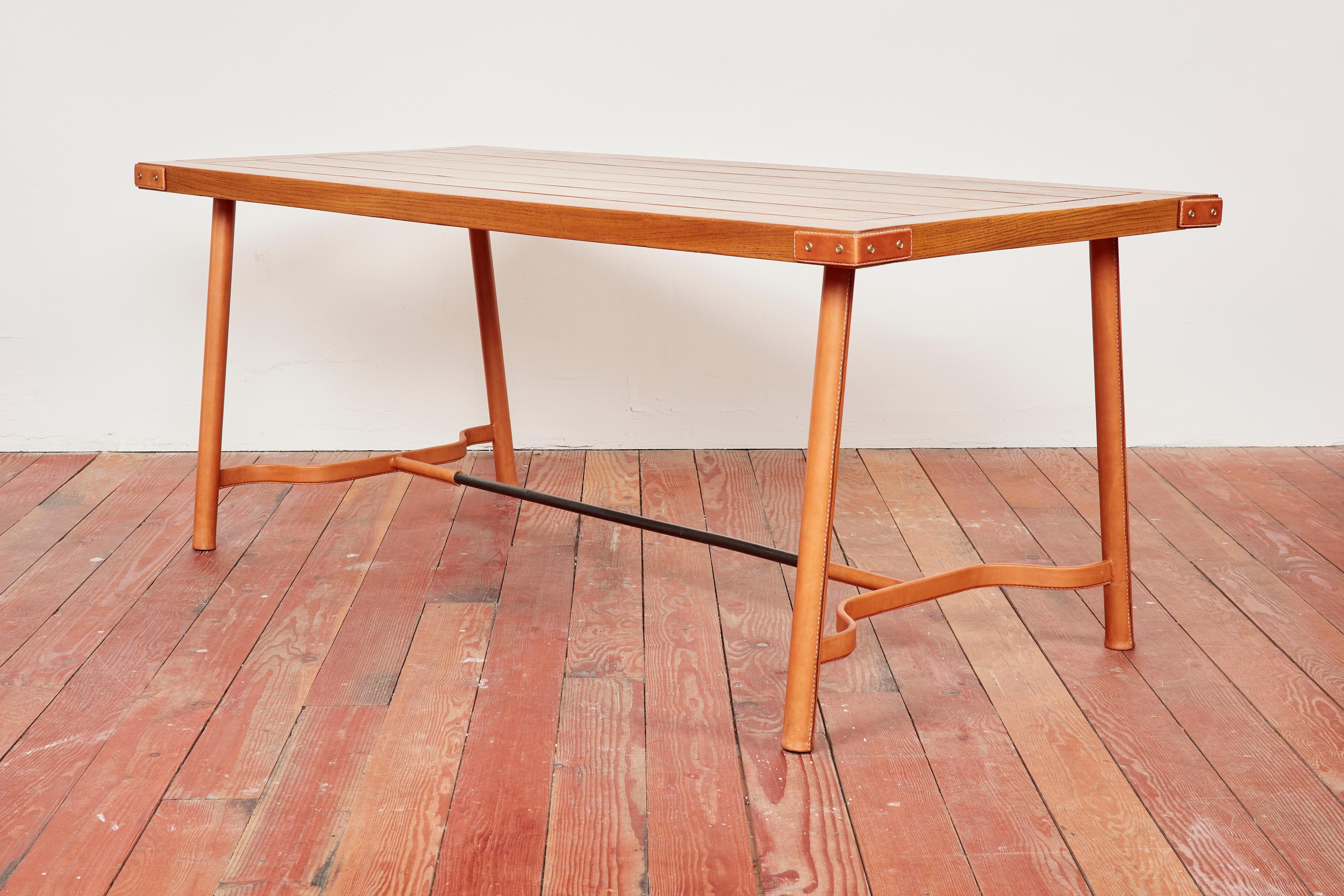 Wunderschöner Tisch von Jacques Adnet, der auch als Schreibtisch verwendet werden kann. 
Wunderschöne Lattenrostplatte aus Eichenholz und charakteristische karamellfarbene Lederbeine mit Kontrastnähten
Neues Leder, das in Frankreich nach den