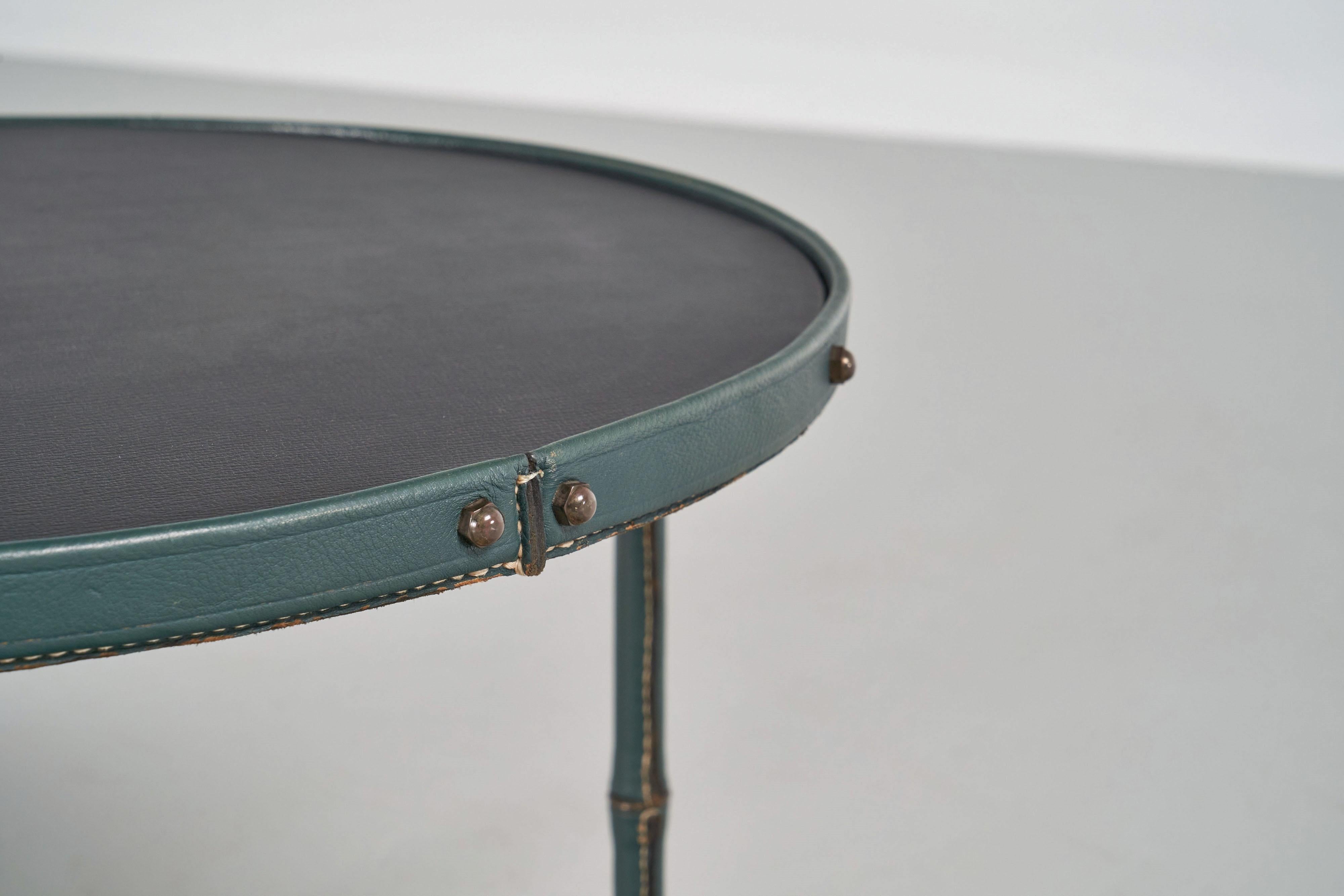 Highly refined full leather covered small coffee or side table designed by Jacques Adnet and manufactured by Ateliers Jacques Adnet, France 1950. This super nice shaped and super quality table has a brass structure frame, fully covered with dark