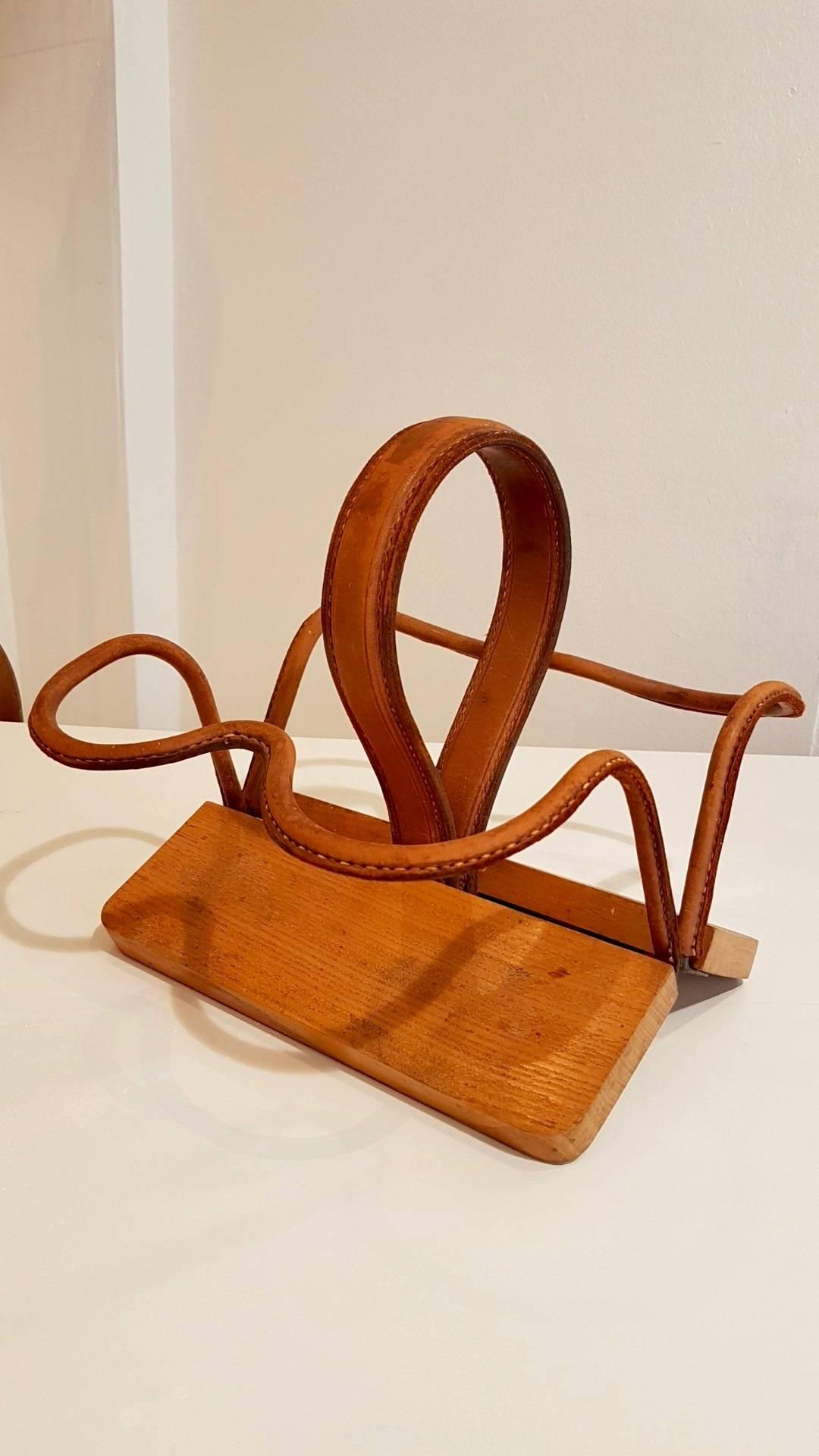 Handsome wine bottle holder by Jacques Adnet. Wood base with leather wrapped frame. Beautiful tabletop object. Excellent condition and patina to leather.