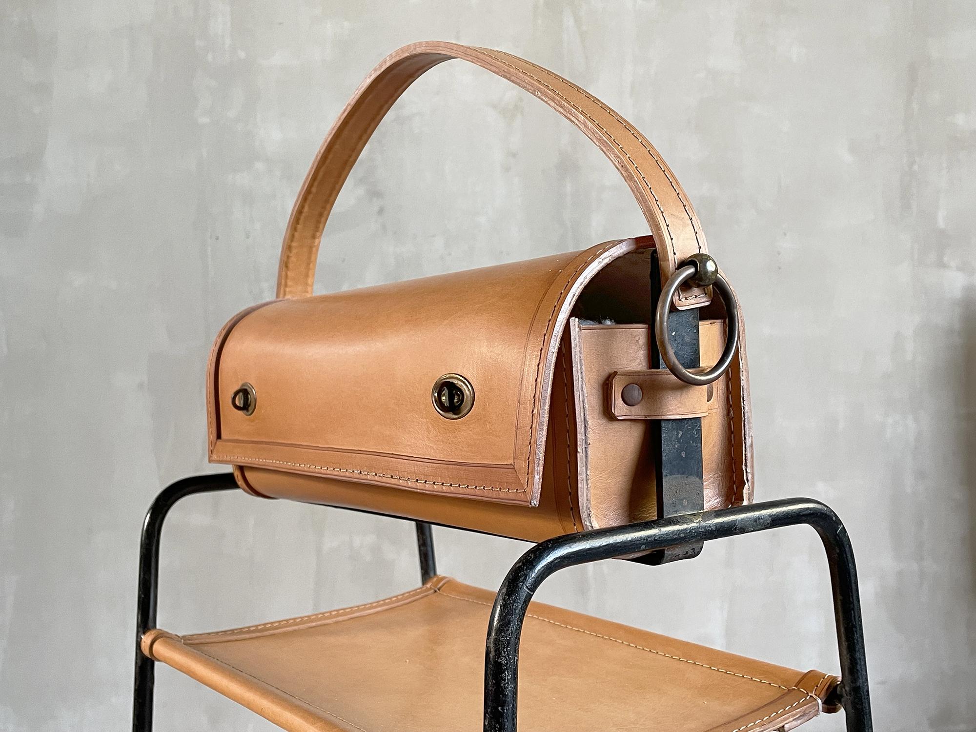 Jacques Adnet (1900-1984), rare sewing box in topstitched fawn leather, structure in black lacquered metal and gilded brass, Compagnie des Arts Français, 1950. The work box is fixed by two large brass rings, below is a shelf in stretched leather.