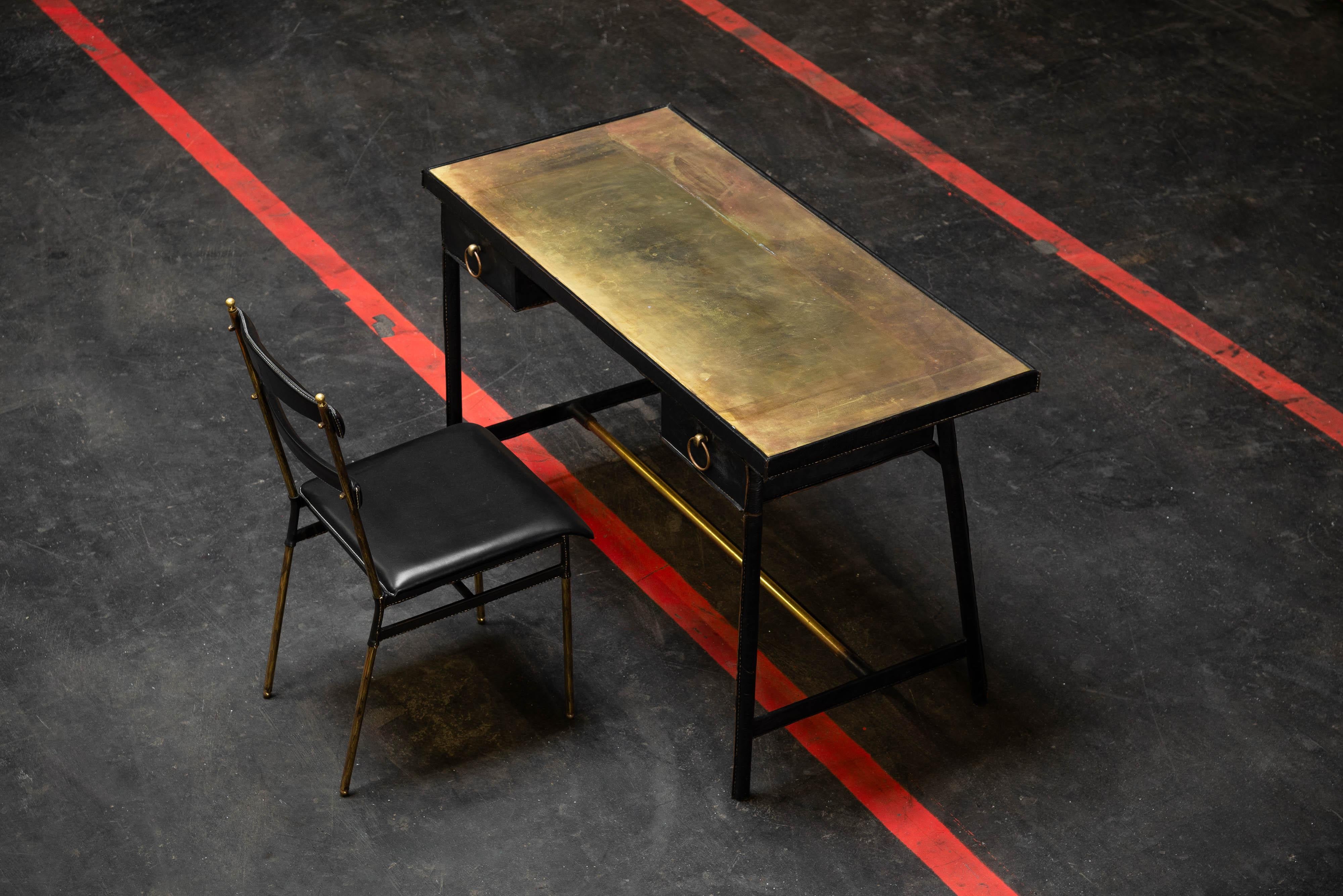 Schöner Avantgarde-Schreibtisch, entworfen von Jacques Adnet und hergestellt in seinem eigenen Atelier in Frankreich in den 1950er Jahren. Der Rahmen besteht aus massivem Messing und ist mit weichem schwarzem Leder umhüllt, was ihm ein edles und