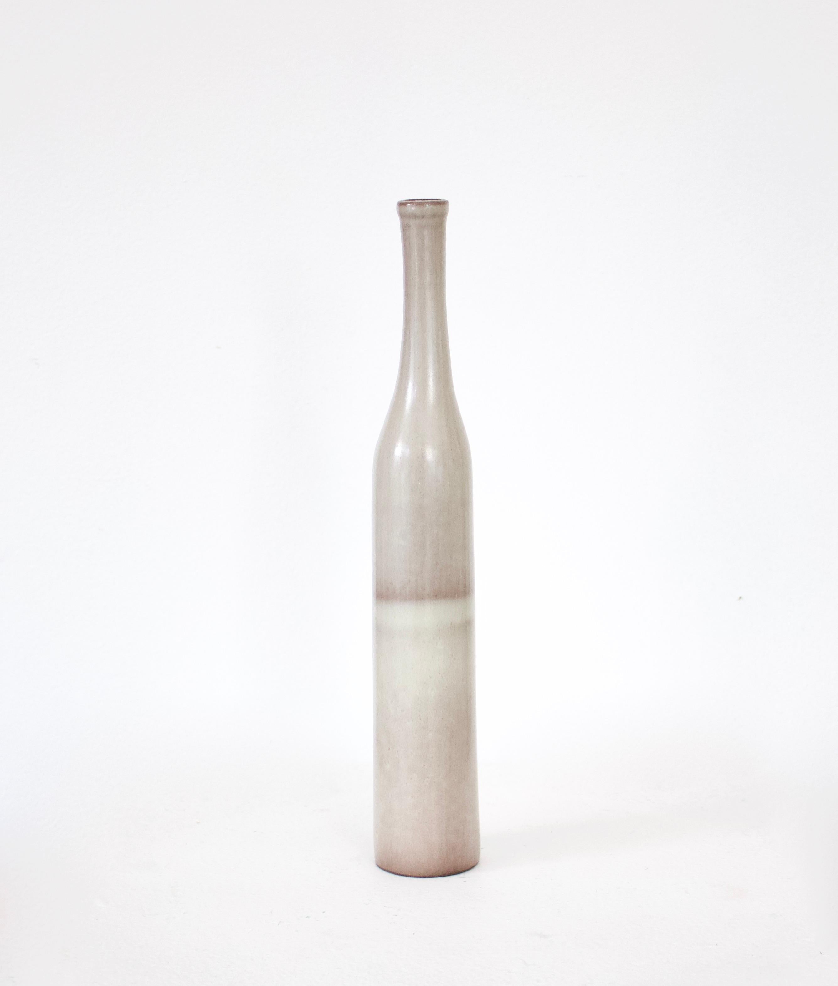 An iconic bottle form by the French ceramic artists Jacques and Dani Ruelland. A pale gray body with a shadow of a stripe with cream white band and then shifting to the palest of gray towards the top. 
Signed.
Literature: Pierre Staudenmeyer, La