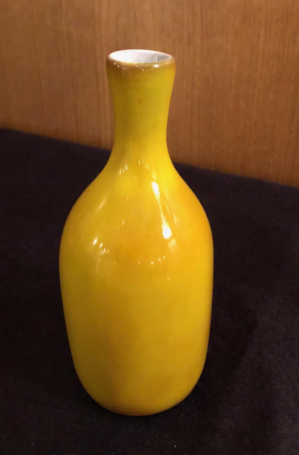 A small bottle form vase by the French ceramic artists Jacques and Dani Ruelland. A yellow orange glaze.