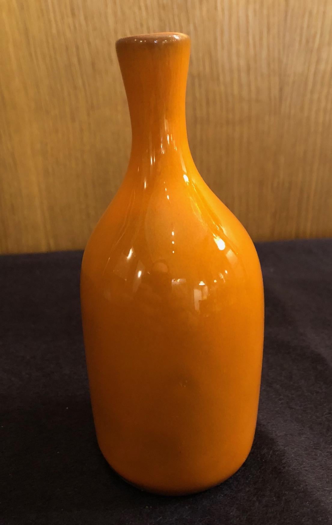 A small bottle form vase by the French ceramic artists Jacques and Dani Ruelland. An orange glaze.