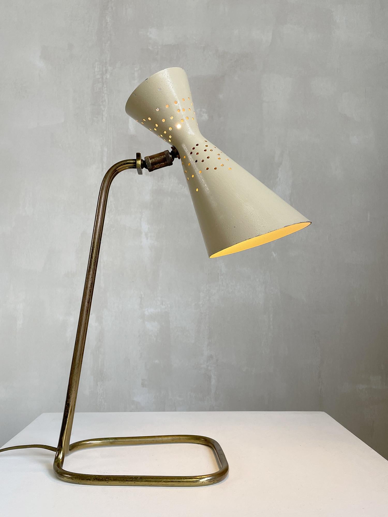 Jacques Biny for Luminalite, extremely rare desk lamp in gilded tubular metal, perforated diabolo reflector, pale yellow and white lacquer. The base is made of a single curved tube and joined at the top by a plate. The double ball joint allows