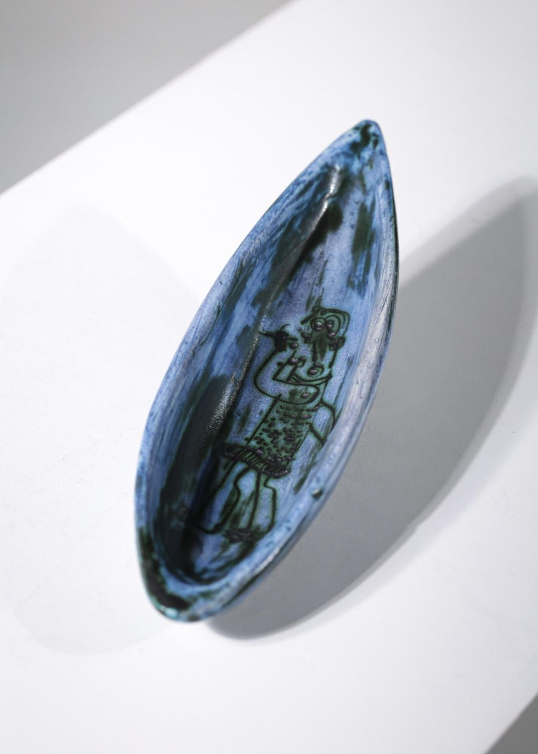 Repose-pipe ou bol en céramique de l'artiste français Jacques Blin datant des années 60. Petite coupe ovale reposant sur deux pieds à émaux dans des tons de bleu typiques de l'artiste, présence d'un dessin représentant un personnage qui fume.