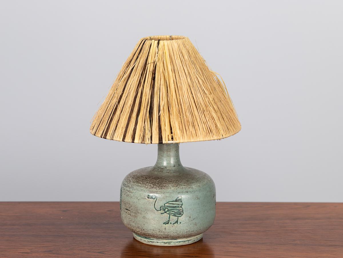 Petite ceramic table lamp with etched bird motif, designed by renowned French ceramicist Jacques Blin. Surface is a mottled seafoam-green glaze, with a quintessential animal motif repeated around the base. The masterful depth of the glaze is
