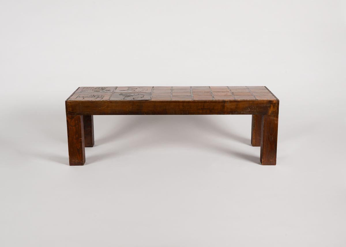 Cette table basse en chêne et en céramique est l'œuvre du célèbre céramiste français Jacques Blin. Elle présente son esthétique dépouillée et ses motifs figuratifs caractéristiques de la peinture rupestre.
