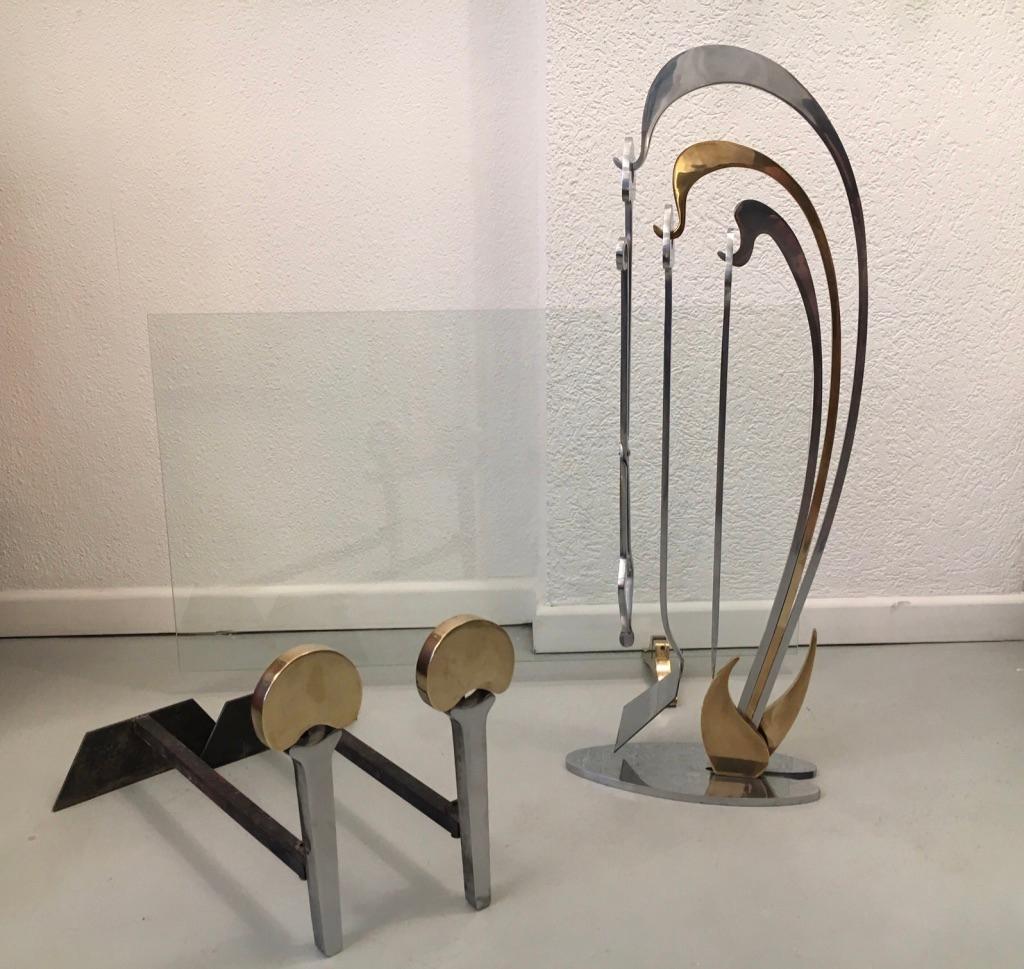 Brass, stainless steel and glass set of firetools by Jacques Charles for Jean Paul Création, France, circa 1970
- Andirons (D 44 x H 30 x l 22 cm)
- Glass firescreen (L 88 x H 54 cm)
- Firetools poker, tongs and shovel (H 83 x L 30 x D 13
