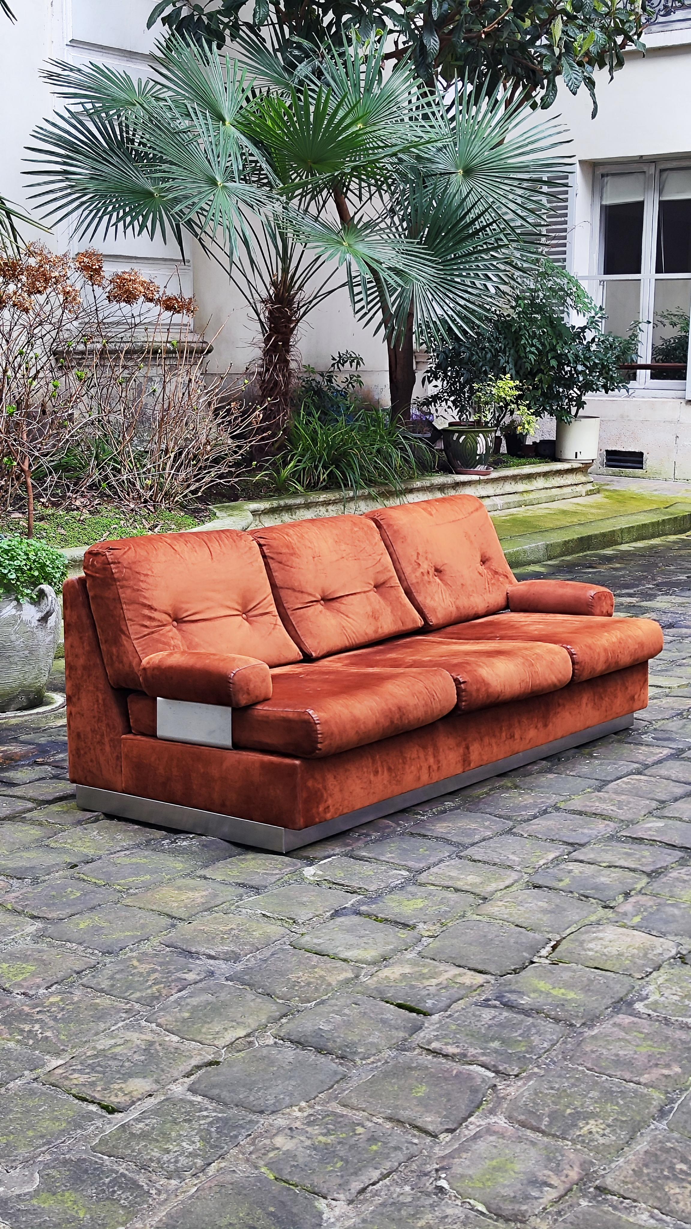 Jacques Charpentier zugeschriebenes Sofa aus hellbraunem Wildleder.

Er besteht aus einem Sockel aus gebürstetem Stahl, einer Struktur und 6 Kissen, die mit einem hellbraunen Wildlederstoff bezogen sind.
Zwei Armlehnen mit Stützen aus gebürstetem
