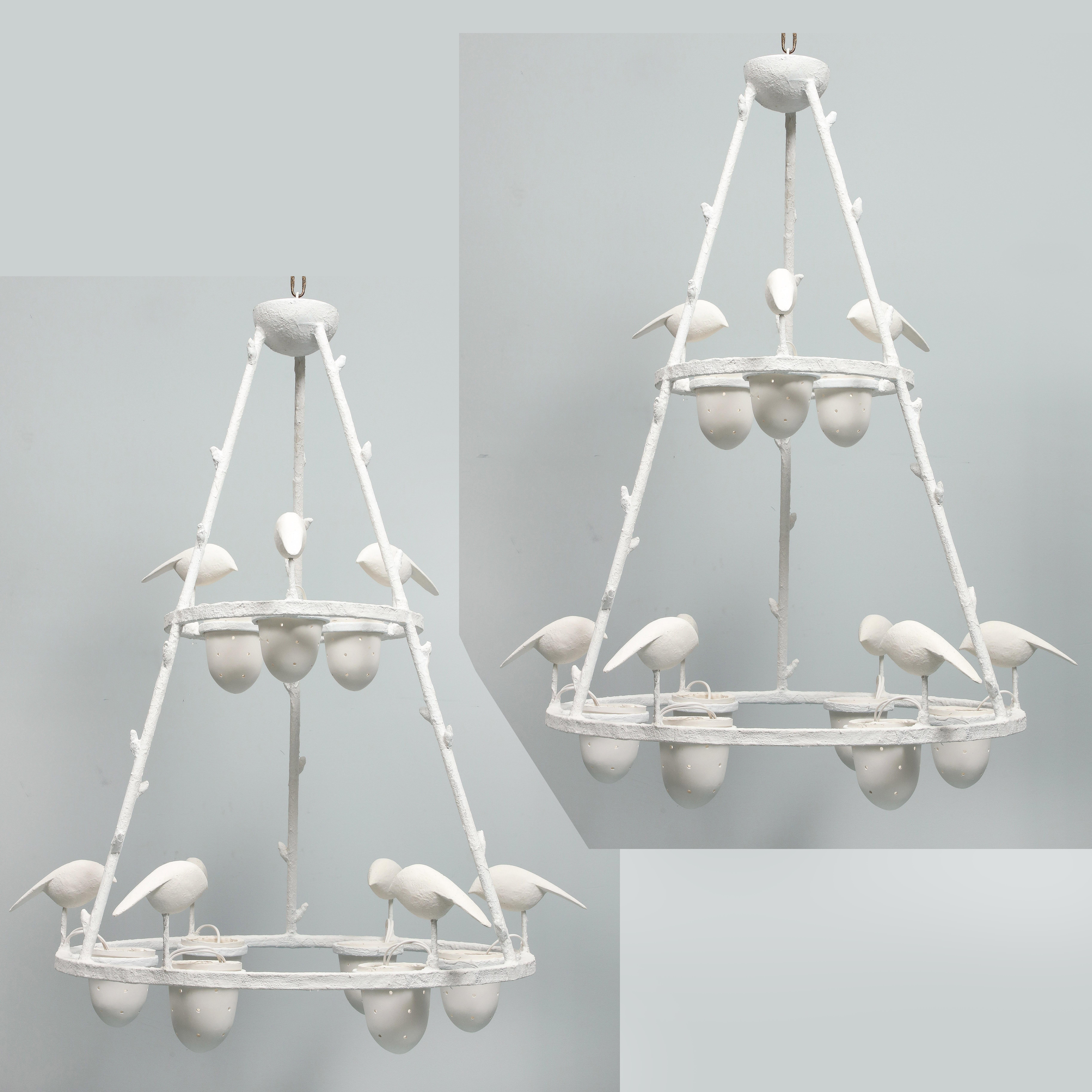 This pair of chandelier is a kind of homage to Giacometti. The structure is in metal covered by white plaster. It has 9 lights, American wired. Birds perch on the frame and peck in a perforated cup which holds the bulb. 