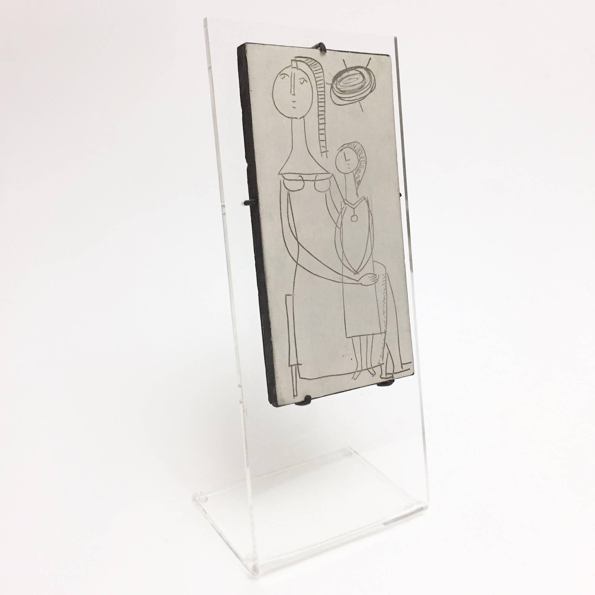 Vallauris red clay tile, glazed in pale grey/beige and black ground decorated with figurative designs engraved. 
The additional and removable clear plexiglass base has been made to measure (contemporary).

The ceramic tile is signed back