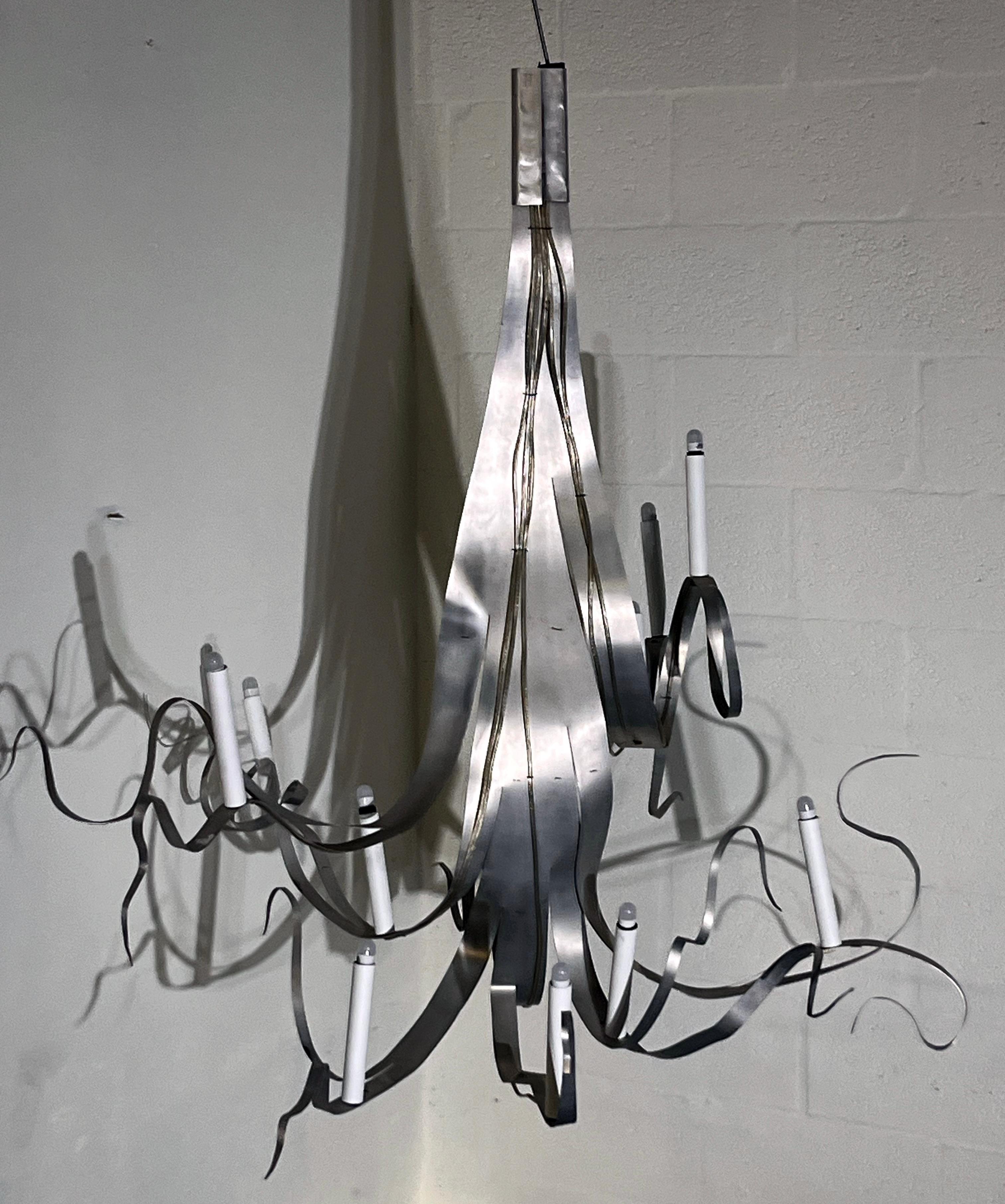 Uno straordinario lampadario scultoreo del designer e artista francese Jacques Jarrige, Francia, primi anni 2000.
Questo apparecchio unico è composto da nastri di metallo sinuosamente attorcigliati, formati a mano per creare un gioco dinamico di