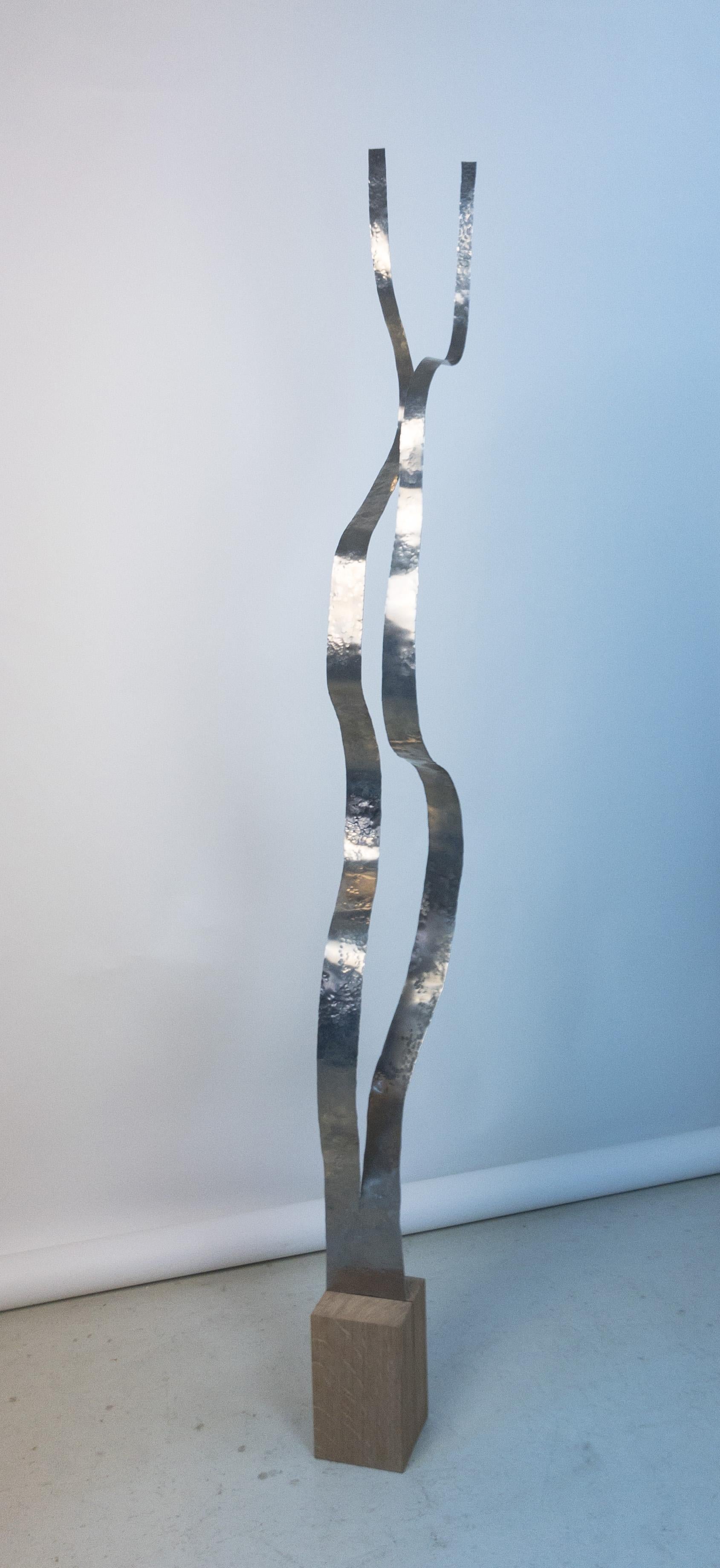 A tall sculpture by Jacques Jarrige. Formed with a strip of aluminum, split and hand hammered the sculpture retains the gesture of the sculptor. 

Set in an oak base.