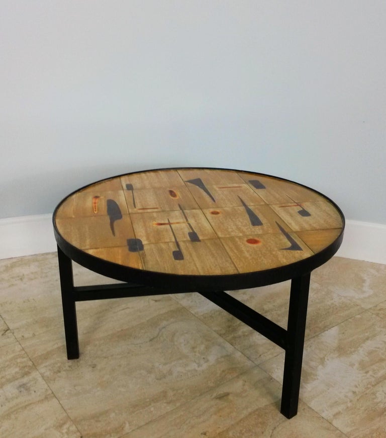Round coffee table by Jacques Lignier. Brown color with black and red abstract forms. Excellent condition. Signed.