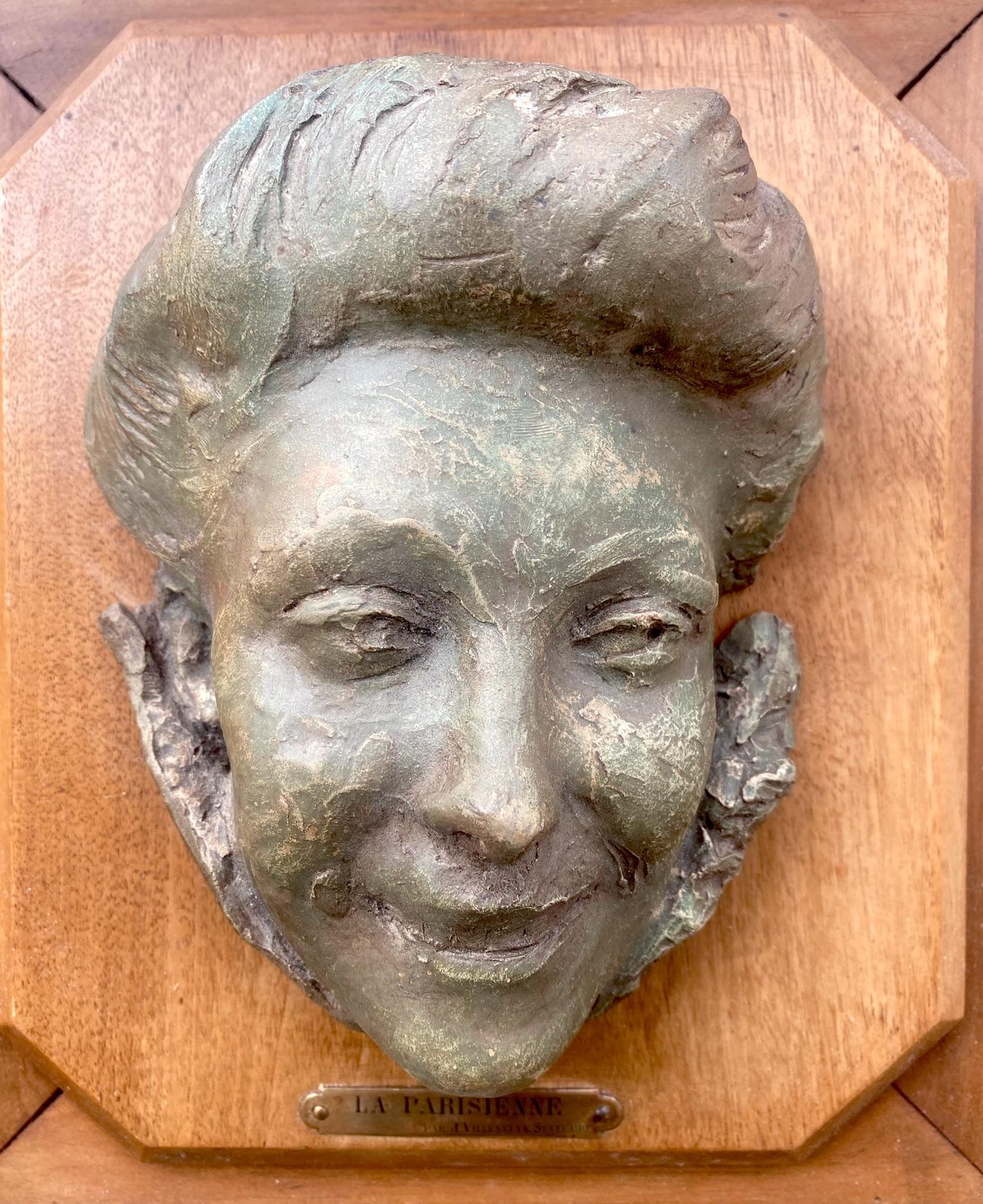 A lovely hand modelled sculpture in bas relief, depicting the head of a smiling young Parisian lady with a gleam in her eyes. The work dates from  from the Belle Epoque, the art nouveau period, ie ca 1900. 
Sculpted in terracotta and patinated