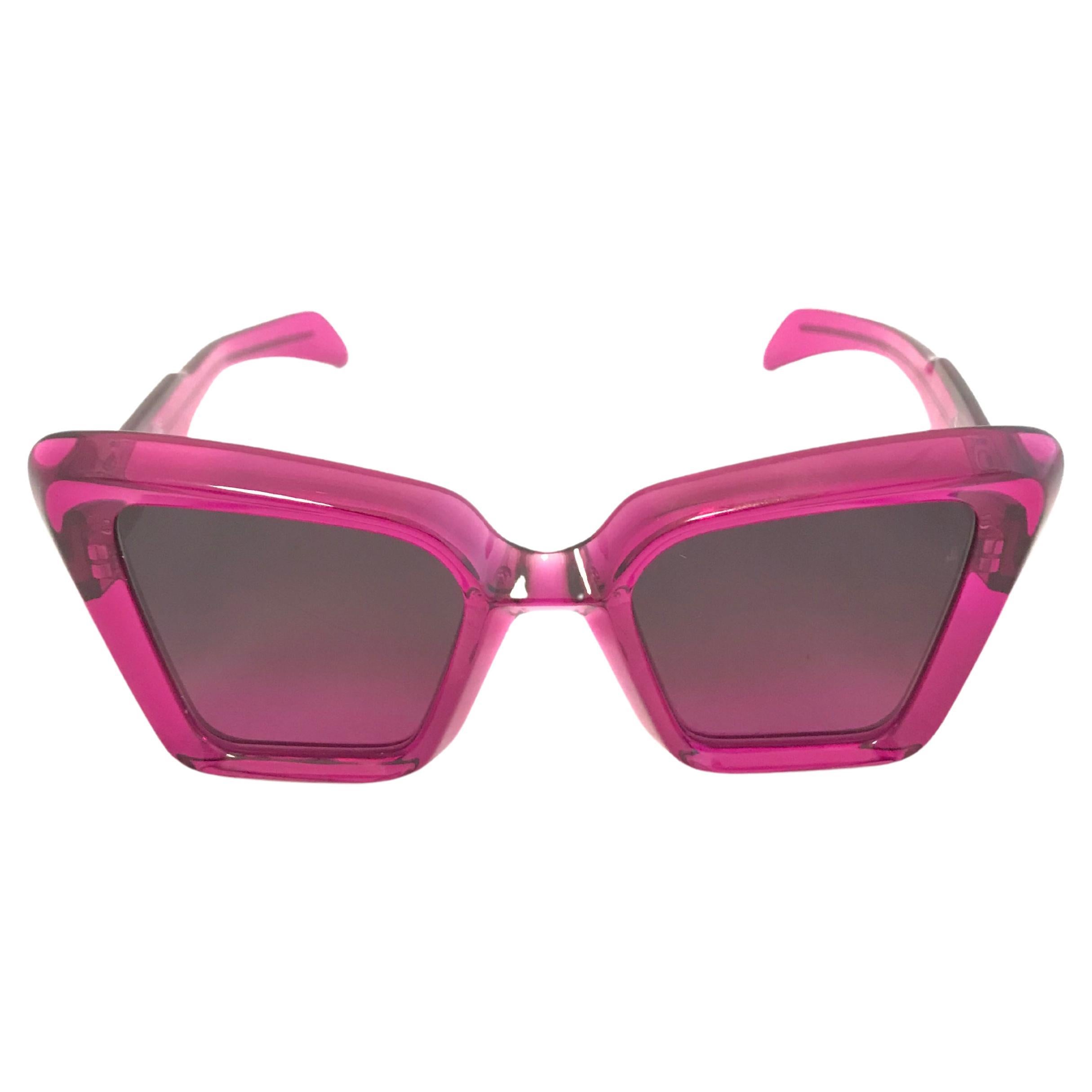 Glossy pink acetate Jacques Marie Mage 'Sly' sunglasses from the eponymous brand. Oversized, chunky, cat eye shape with a subtle black and pink ombre tint on the lens. Legs are acetate with slim silver strips running along, encased in the acetate,