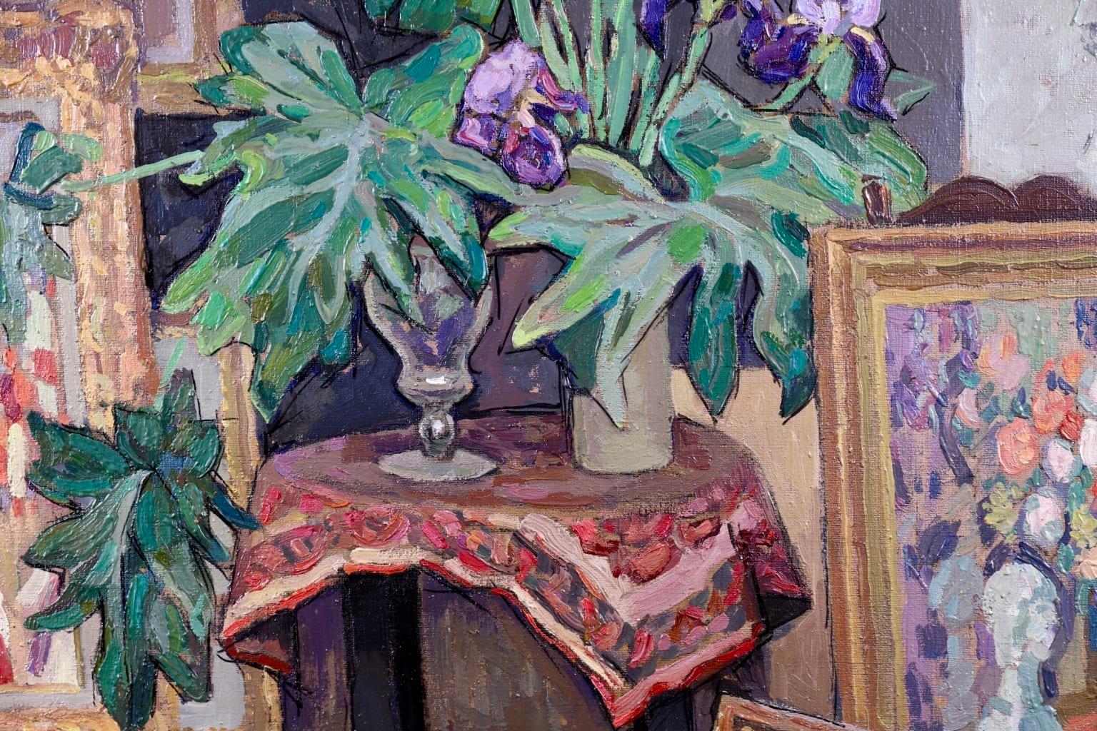A wonderful oil on original canvas circa 1930 by French post-impressionist painter Jacques Martin-Ferrieres depicting a view of the artist's study. There is a wooden table set on the patterned rug, on top of which is a vase of purple and red &