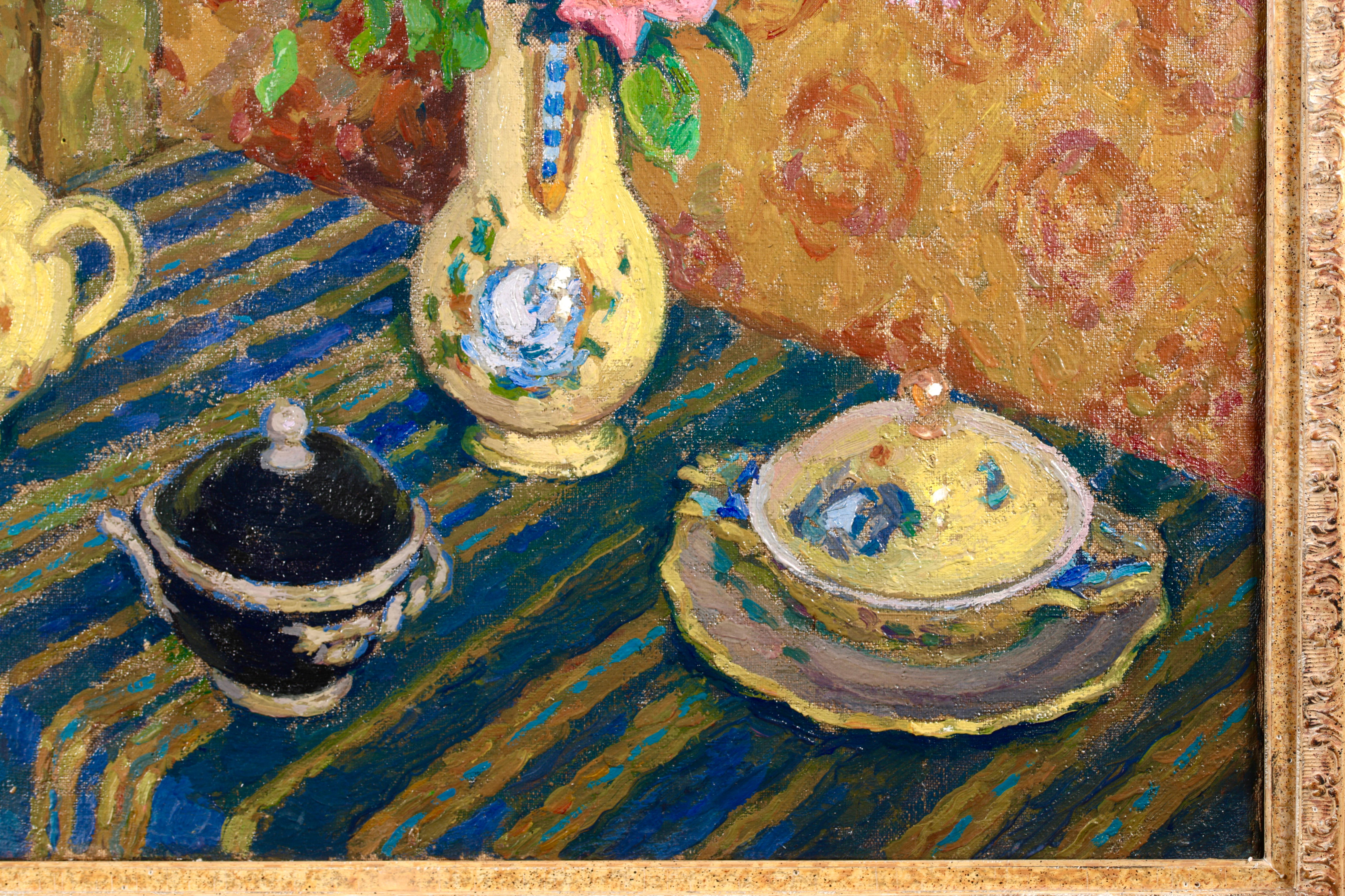 Beautiful still life oil on canvas circa 1940 by French post impressionist painter Jacques Martin-Ferrieres. The work depicts a table covered with a blue and gold striped cloth. Resting on the table is a set of yellow pottery with blue flowers,