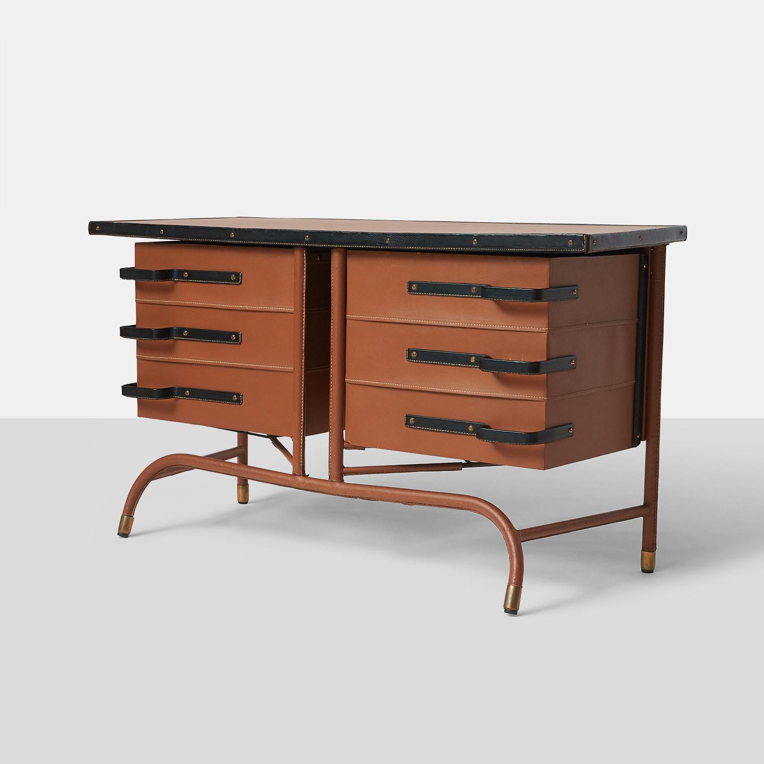 Jacques Quinet Commode
A unique cabinet or credenza with two doors that swing open from the center. Each door contains horizontal storage shelves, and the entire cabinet is wrapped in tan saddle stitched leather with black leather handles. 
This