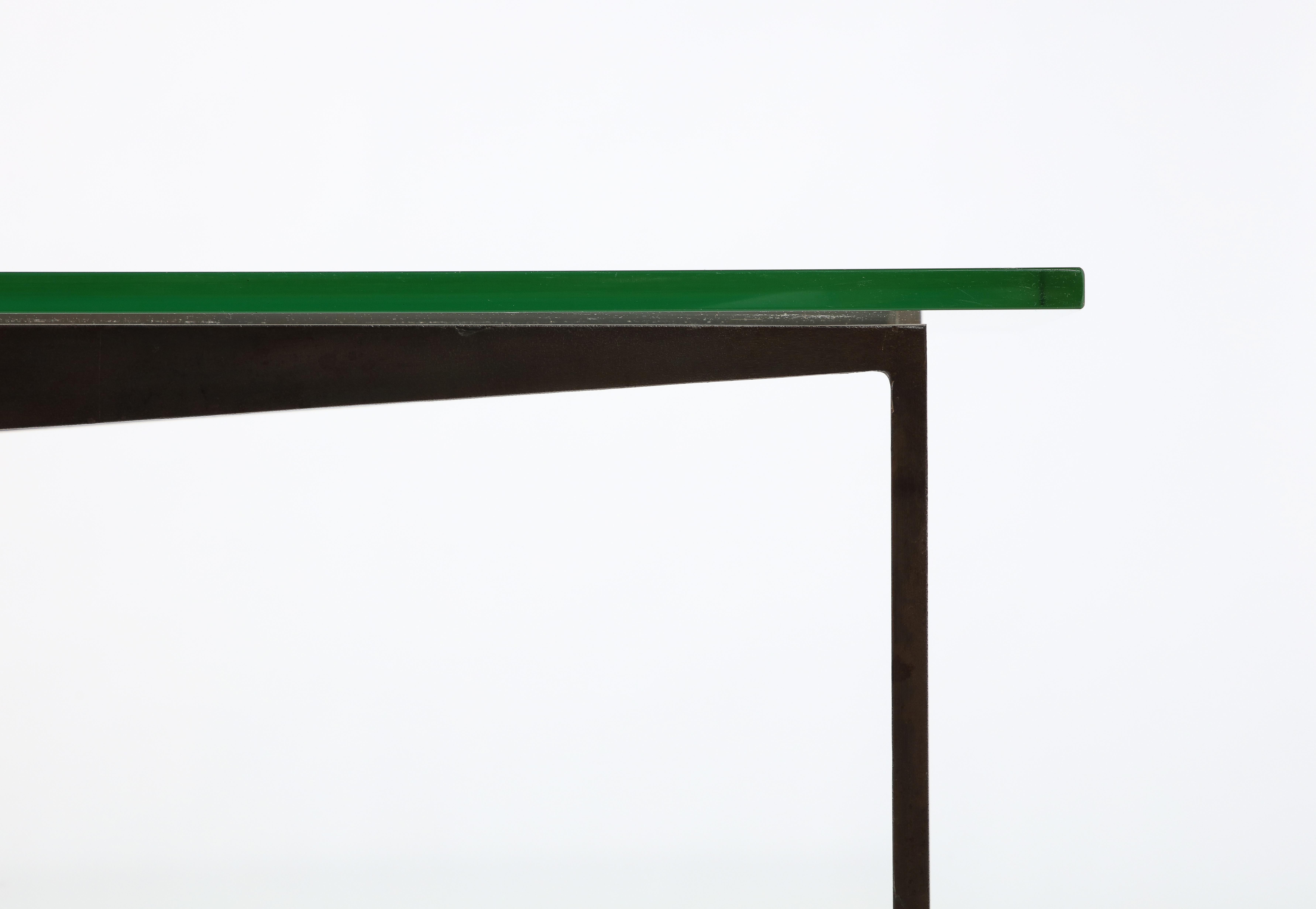 Large patonated iron table by Jacques Quinet with angled stretchers and tapered legs with brass sabots; Top is Saint Gobain glass with a chartreuse tint.