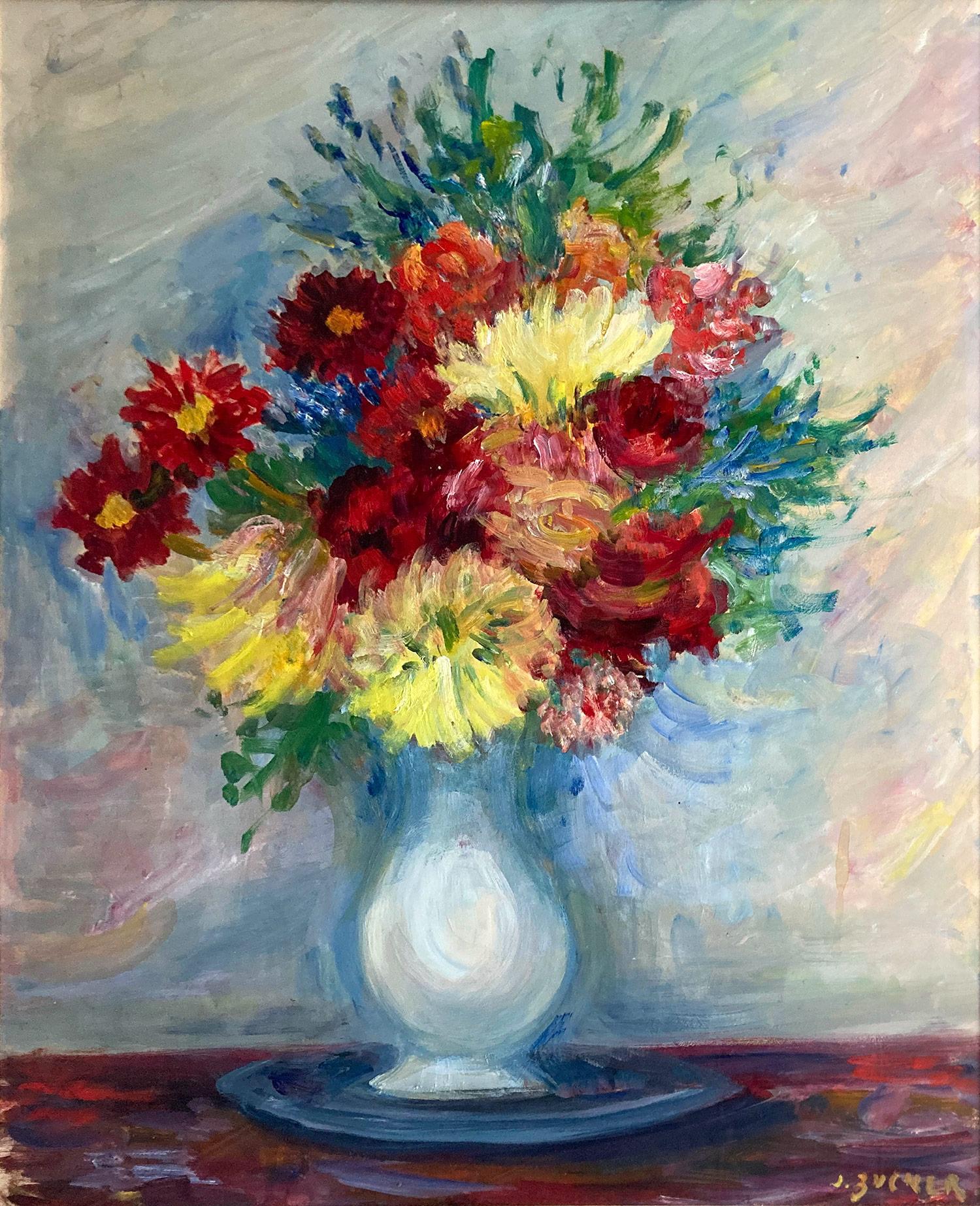 A charming oil painting on paper depicting a colorful floral still life in a white vase on top of a wood table. The flowers depicted are a bright bunch of carnations, daisies, greenery red roses.  The bright colors and quick brush strokes are what